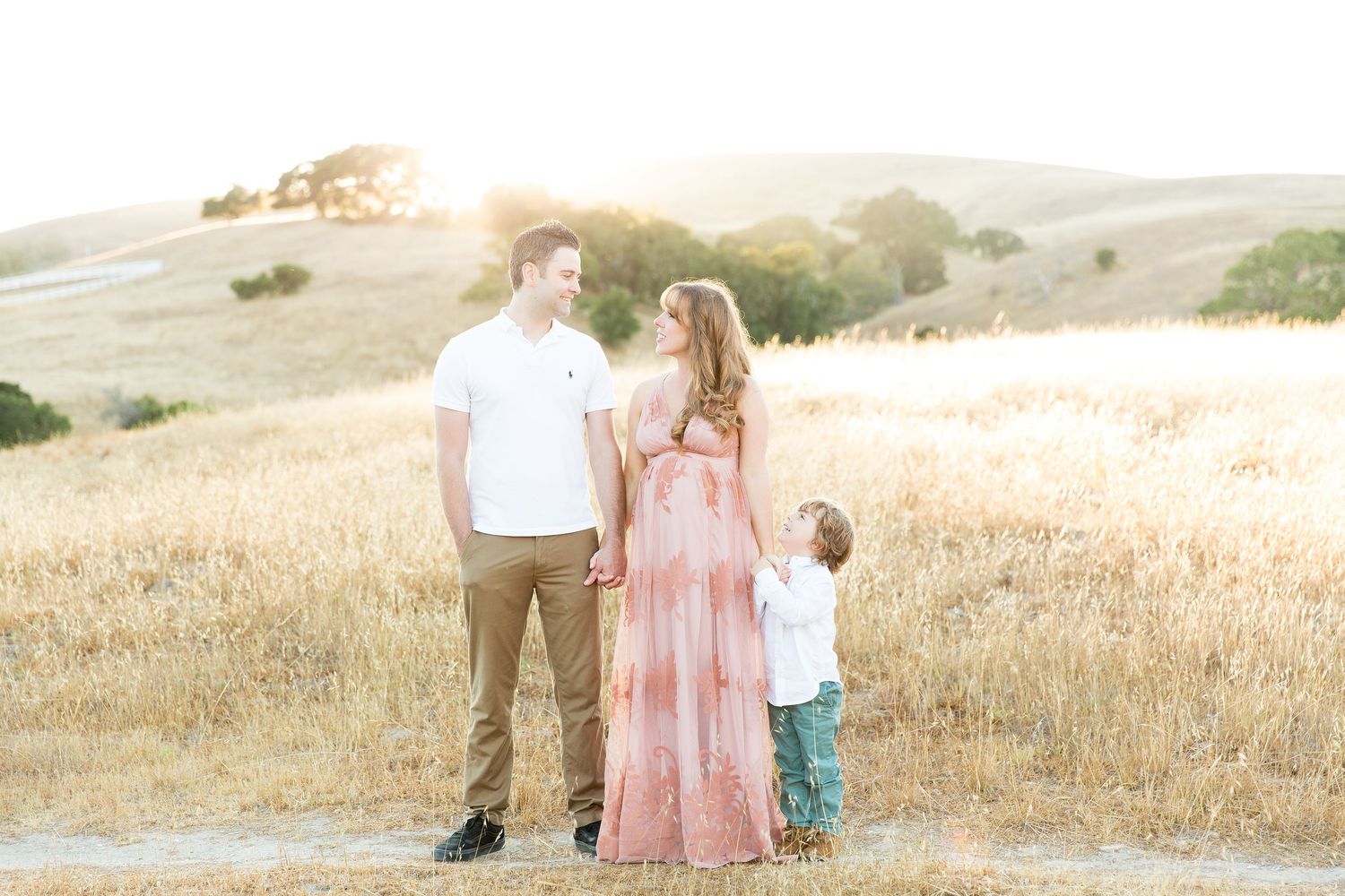 Family standing together in golden field during sunset photoshoot.