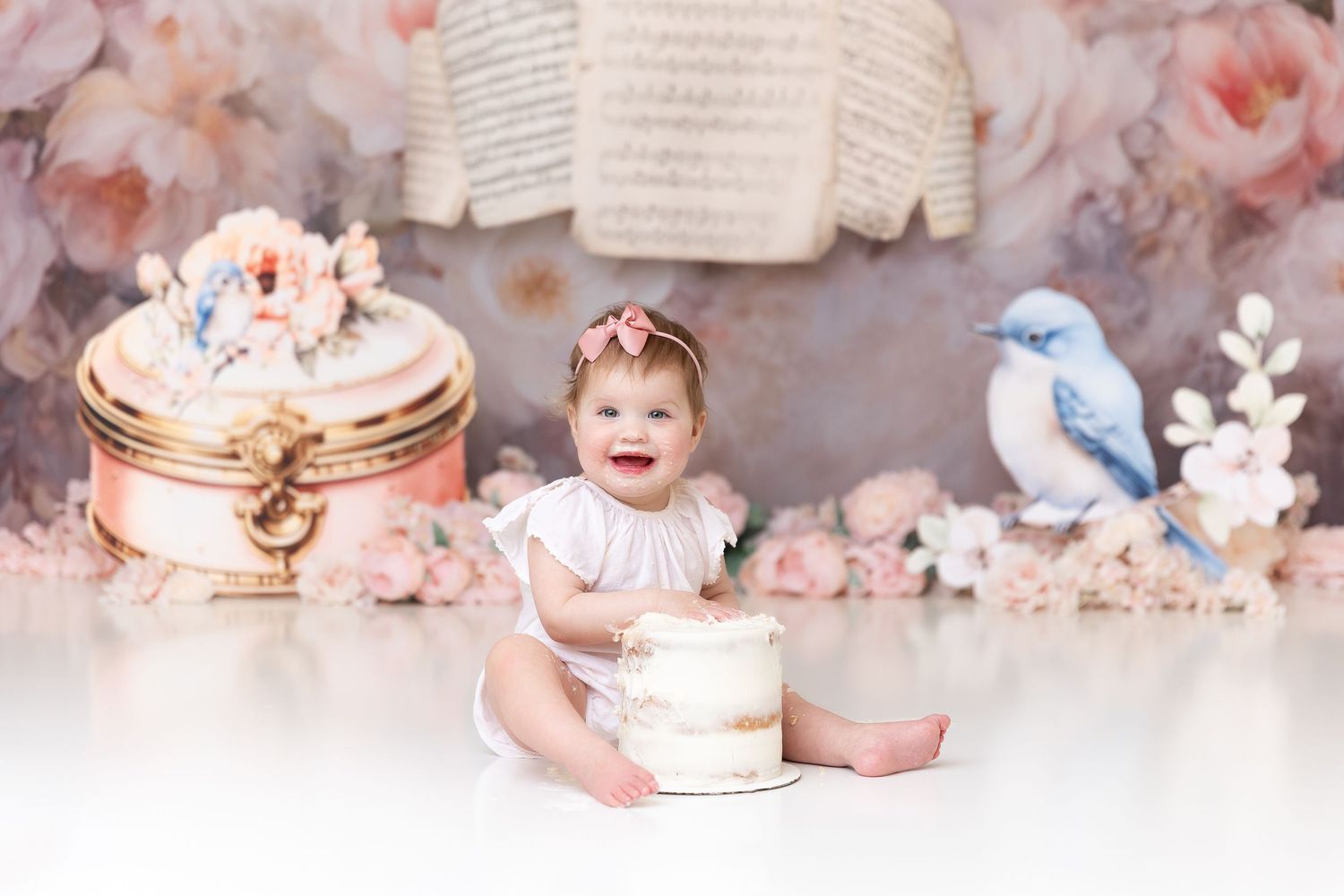Whimsical first birthday scene with cake, books, and pink floral accents.