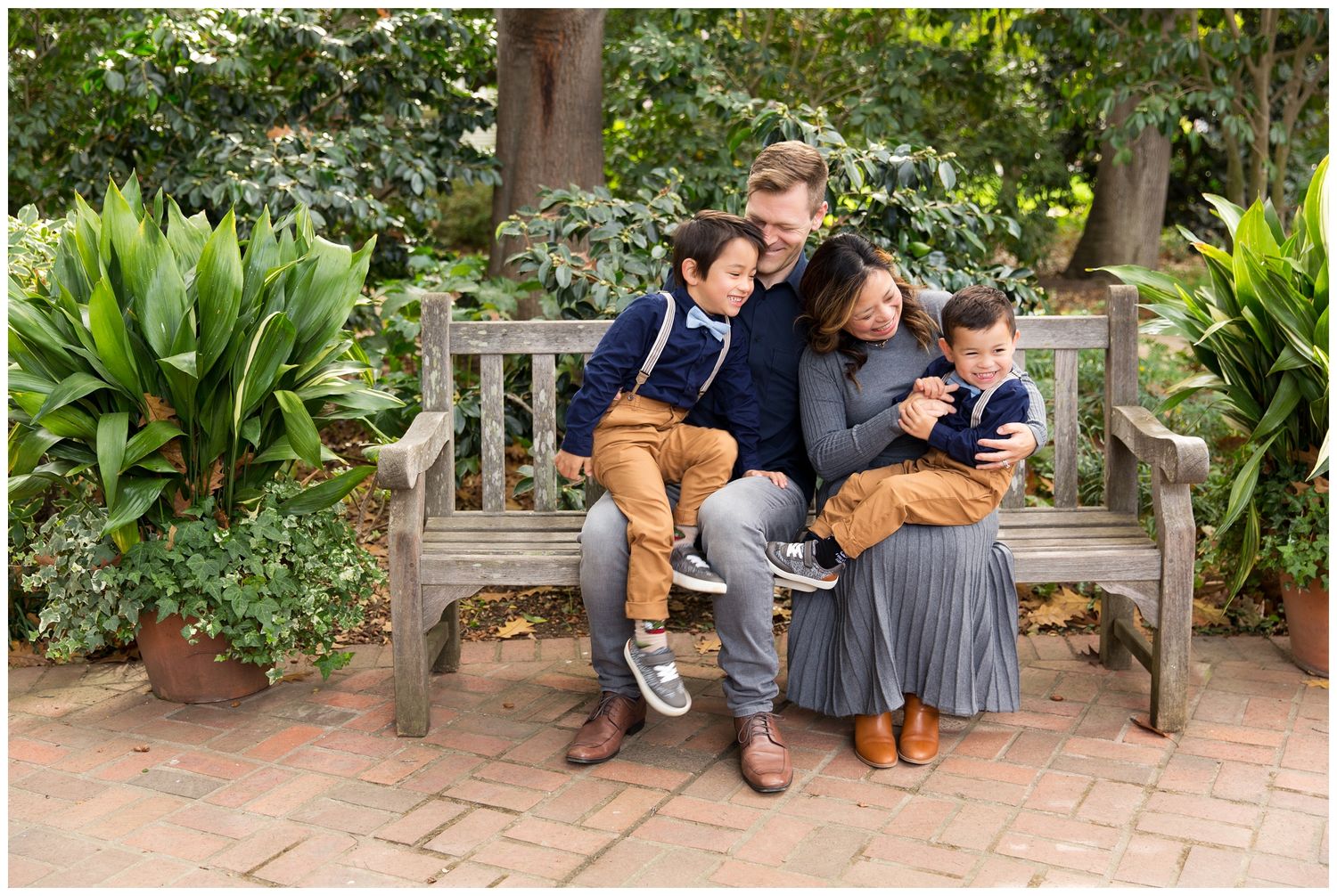 Students in school uniforms sitting on benches in a lush garden setting during a sunny day.