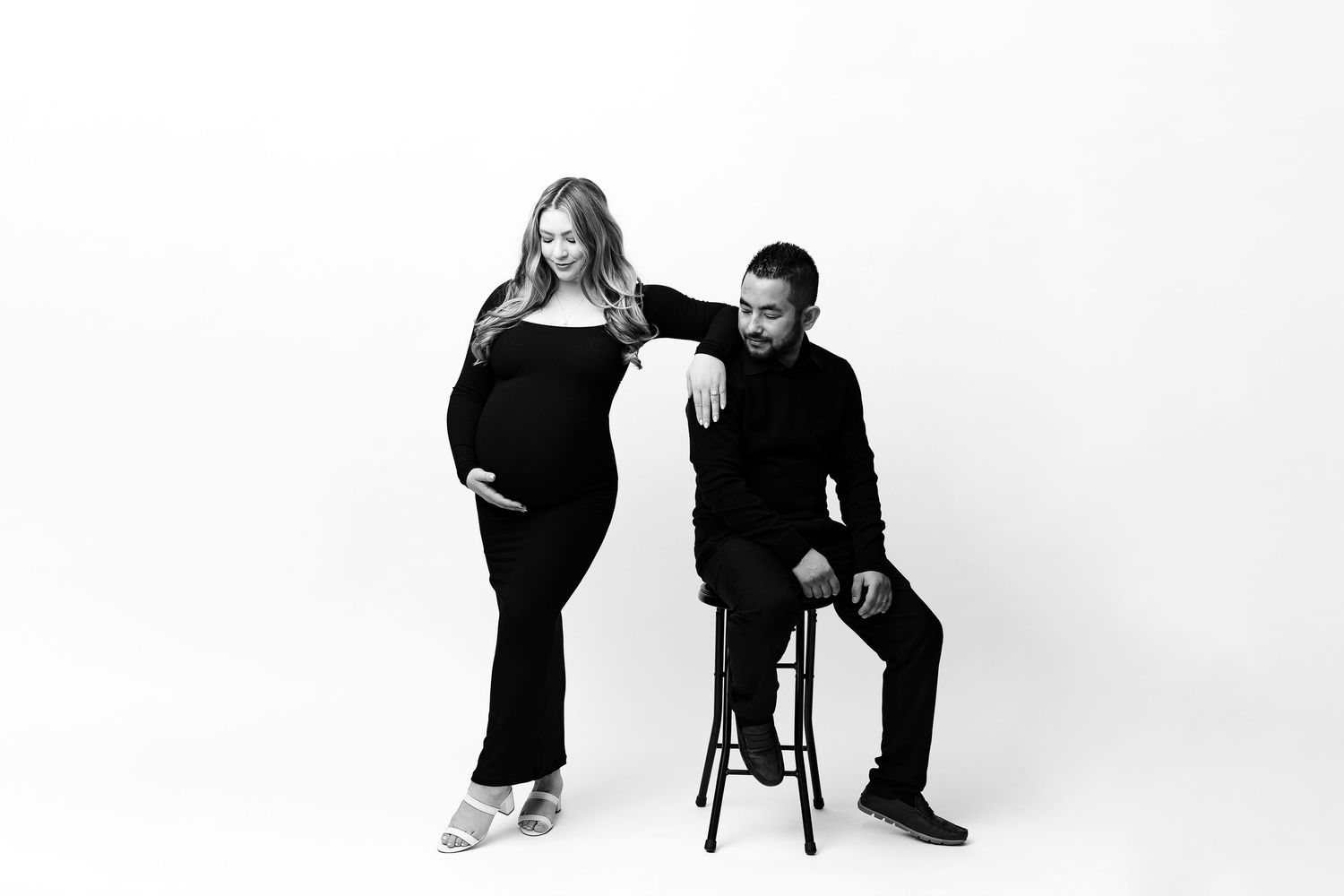 A maternity couple pose together in a minimalist black and white studio photoshoot in Monterey.