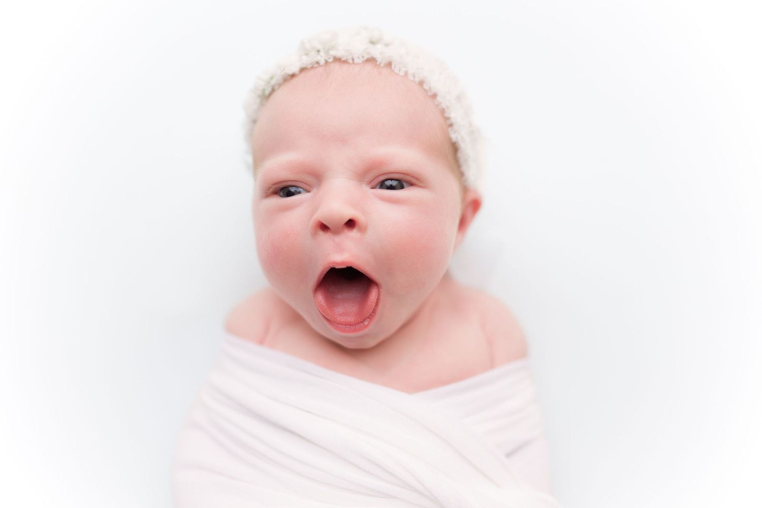 Happy infant making playful expressions on clean white background.