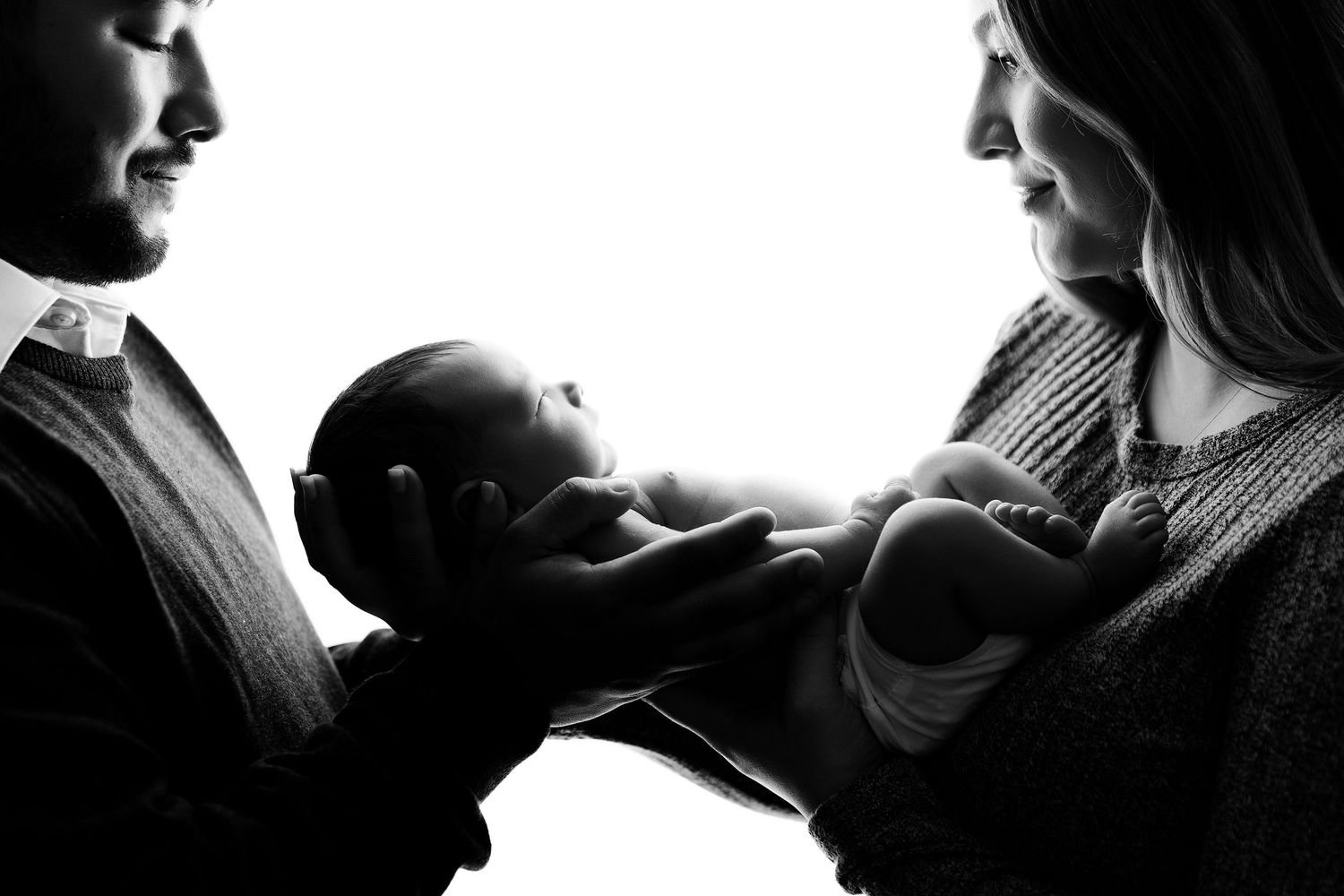 Silhouetted profiles of mother and baby in intimate black and white photography.