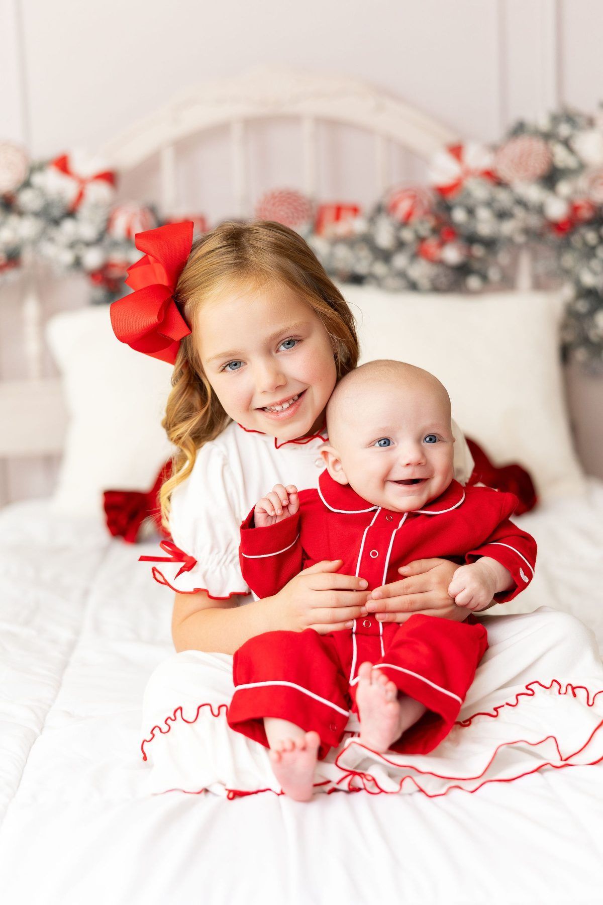 Big sister holding baby brother in red Christmas pajamas, Monterey Christmas mini session