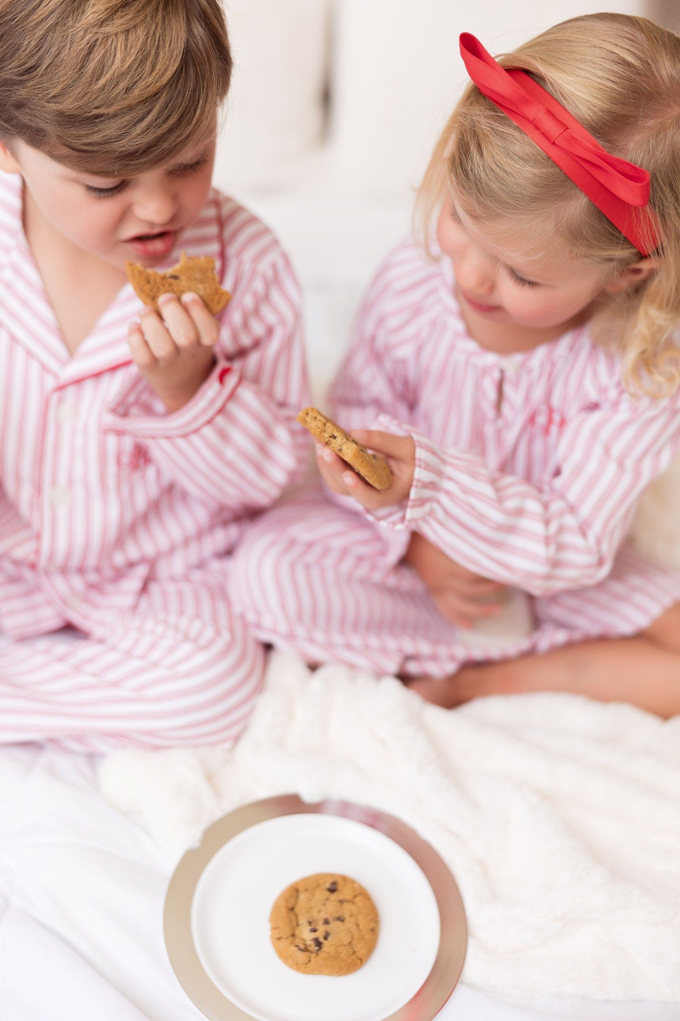 Two kids in matching holiday jammies sharing milk and cookies at a Christmas mini session in Pacific Grove