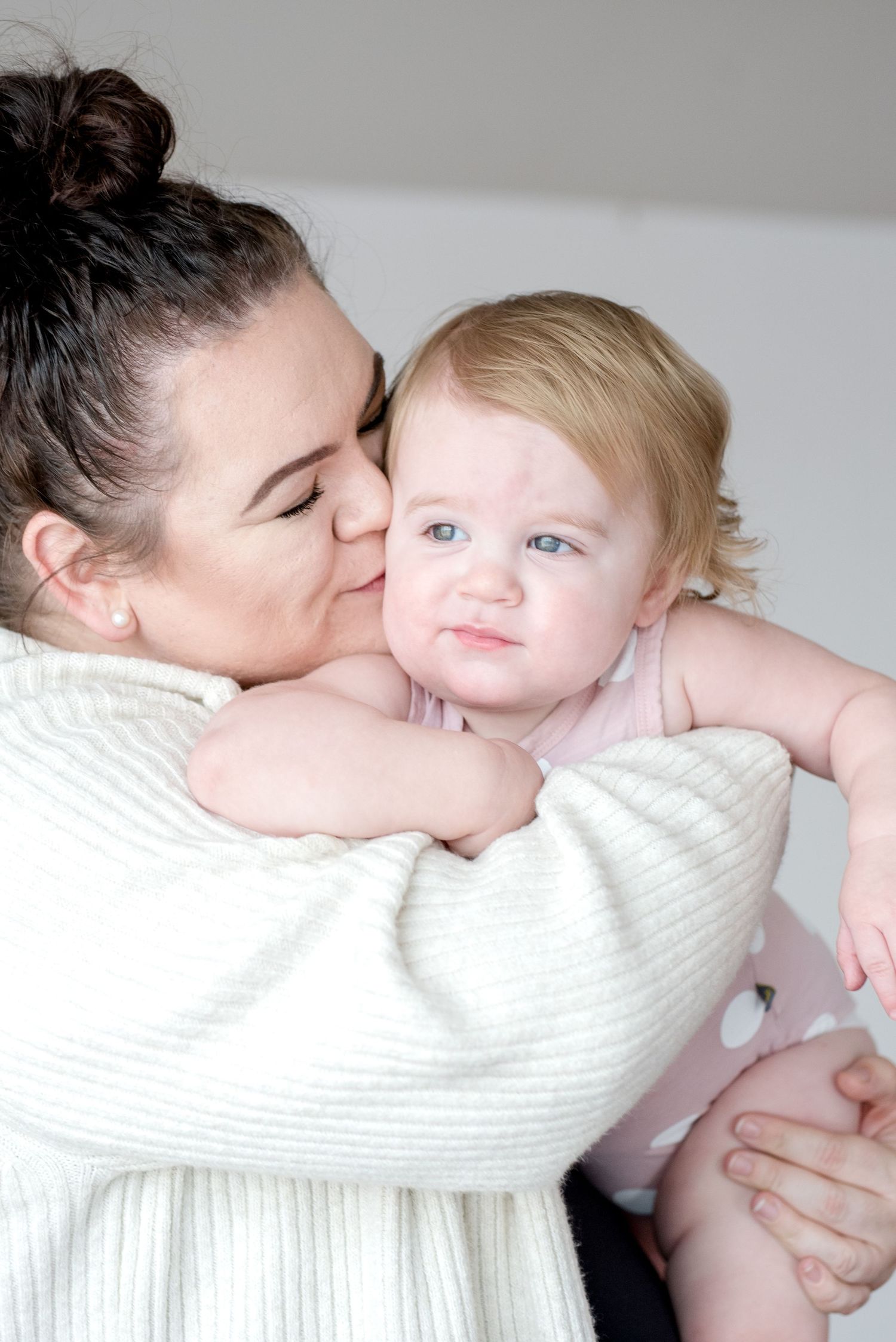 Tender moment captured in white against grey studio background.