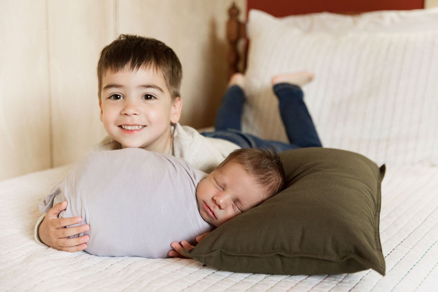 Cozy lifestyle portraits showing siblings lounging on white bedding.