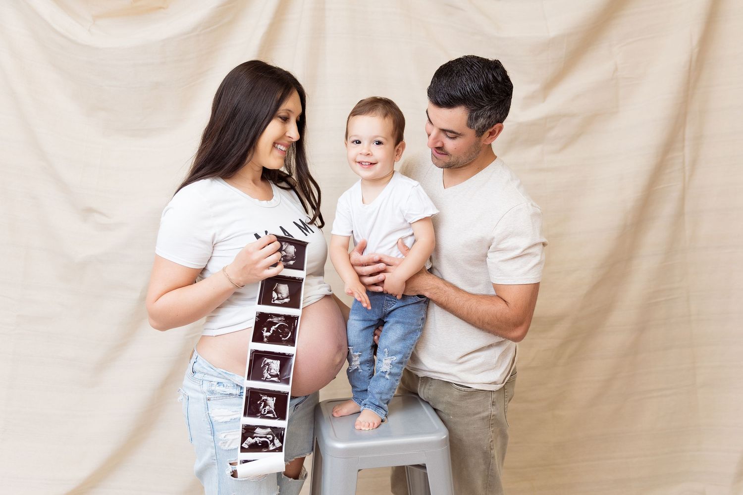 Family pregnancy announcement photos showing ultrasound images in casual home setting.