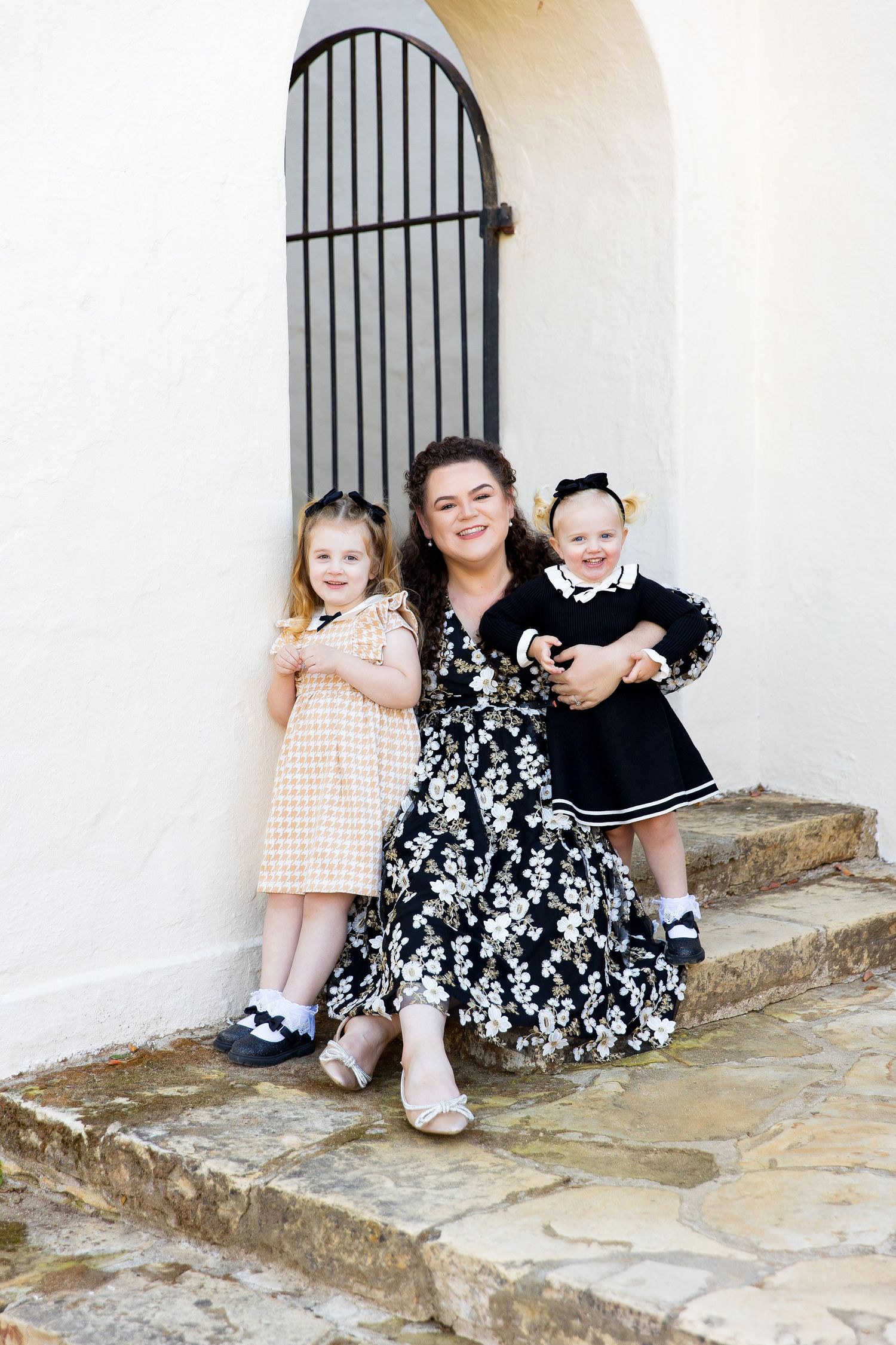 Family portrait on stone steps with wrought iron gate in background, in Monterey.
