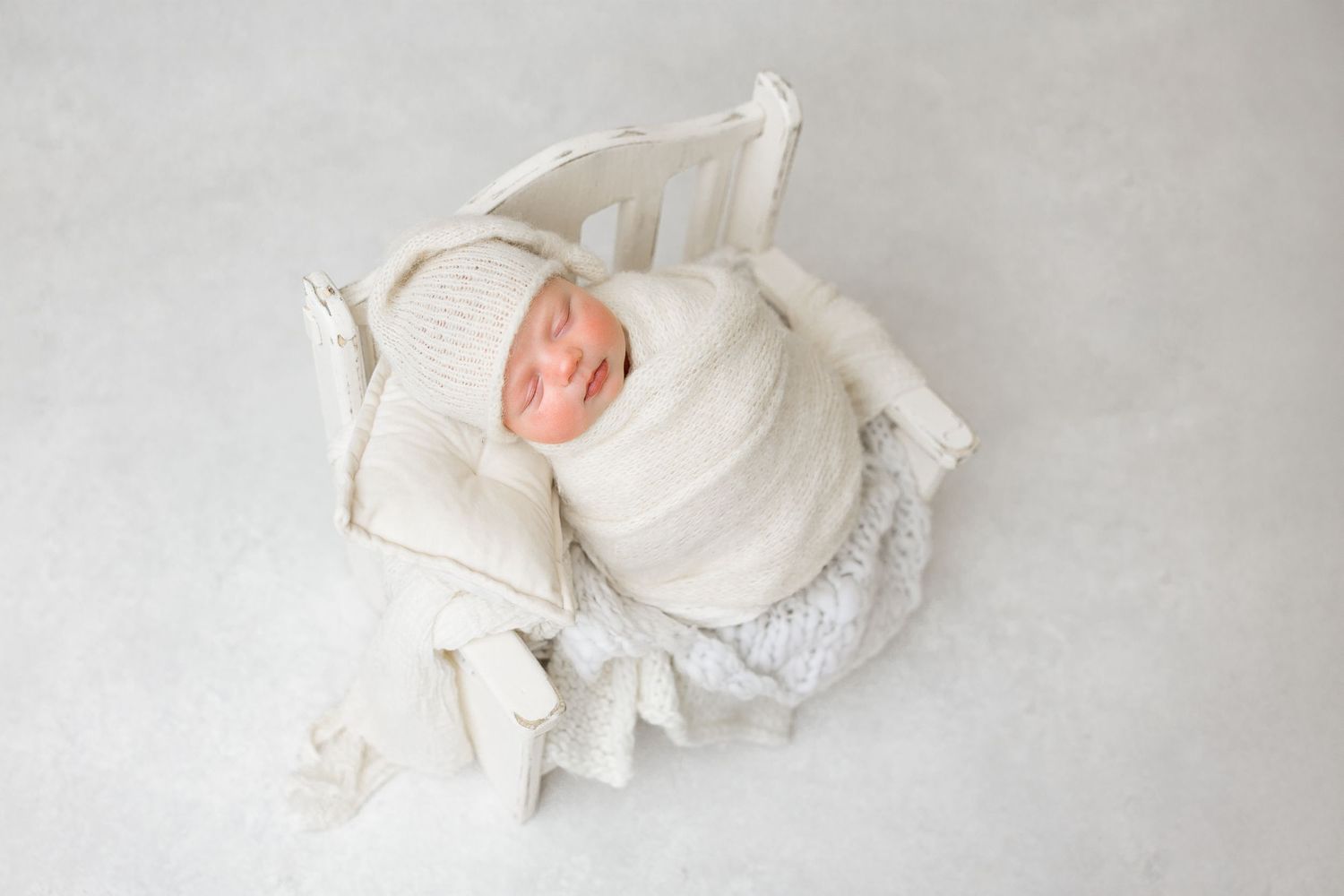 Delicate white rose petals arranged in a soft, romantic composition against a light gray background.