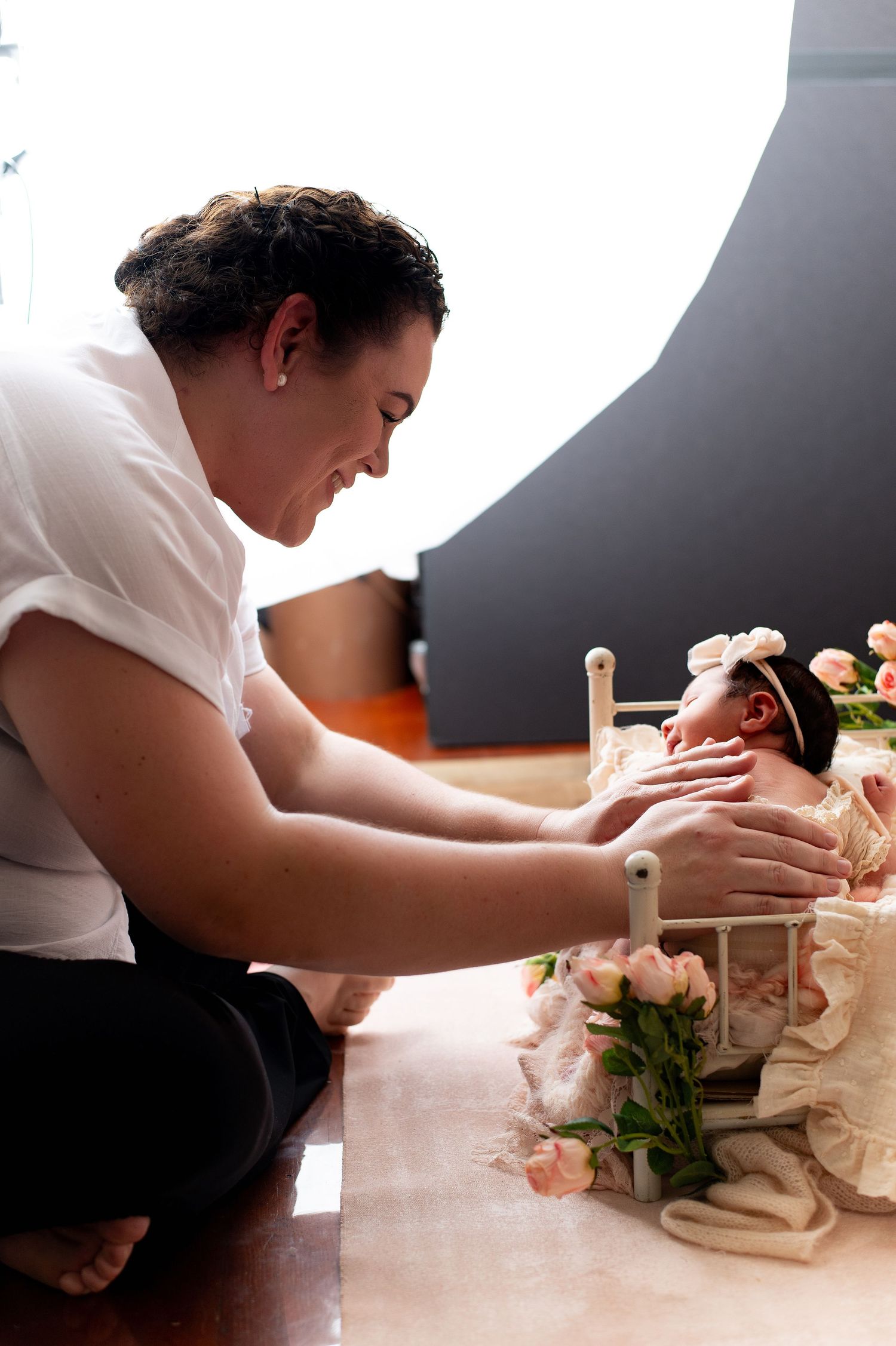 A person in a white shirt carefully arranges delicate pink roses in a decorative display.