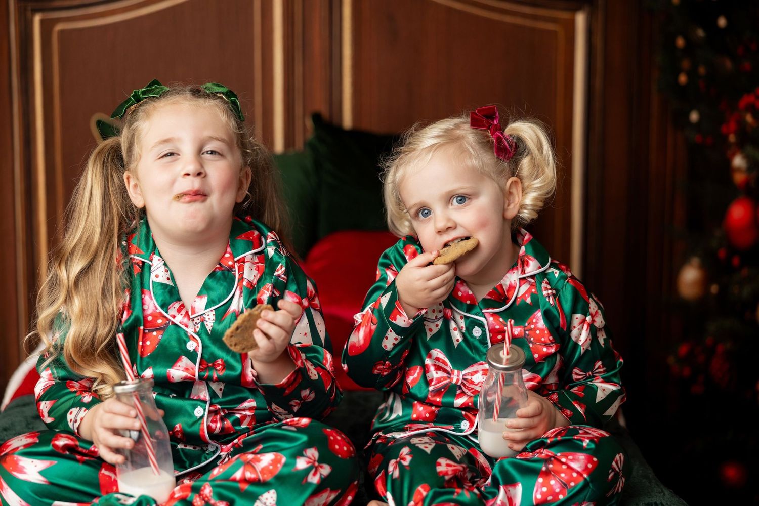 Two girls in matching green Christmas jammies with milk and cookies at a holiday mini session in Pacific Grove