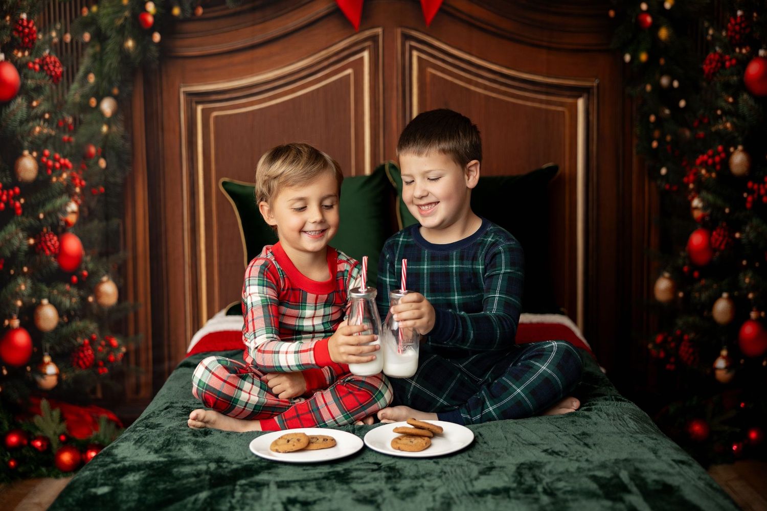 Two boys in Christmas pajamas sharing milk and cookies by the holiday trees at a mini session in Pacific Grove