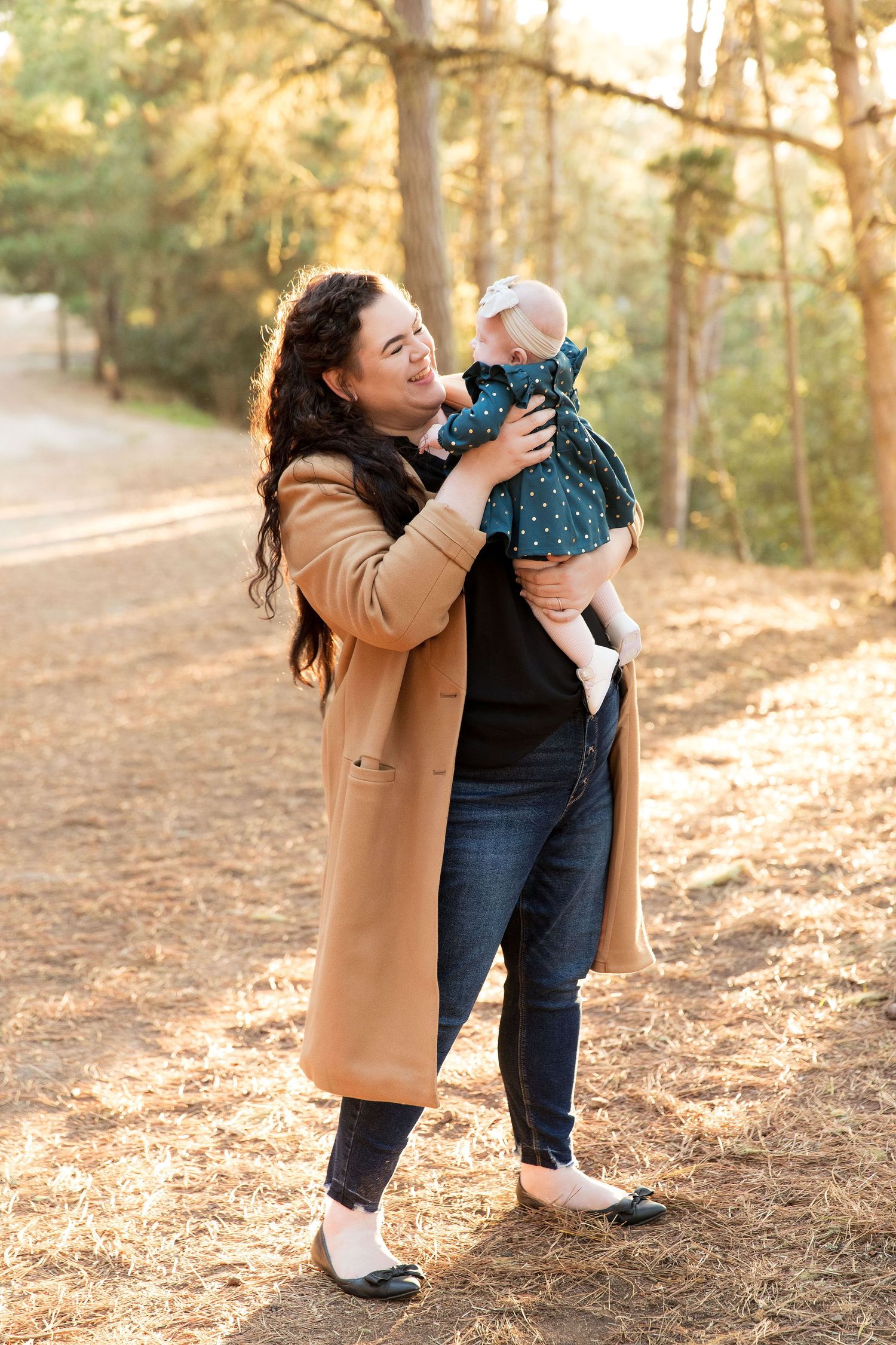 Family photography session in sunlit forest with warm autumn tones.