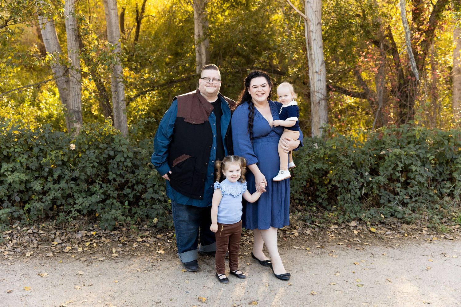 Family poses together on autumn trail with golden trees in background, in Carmel Vallery.