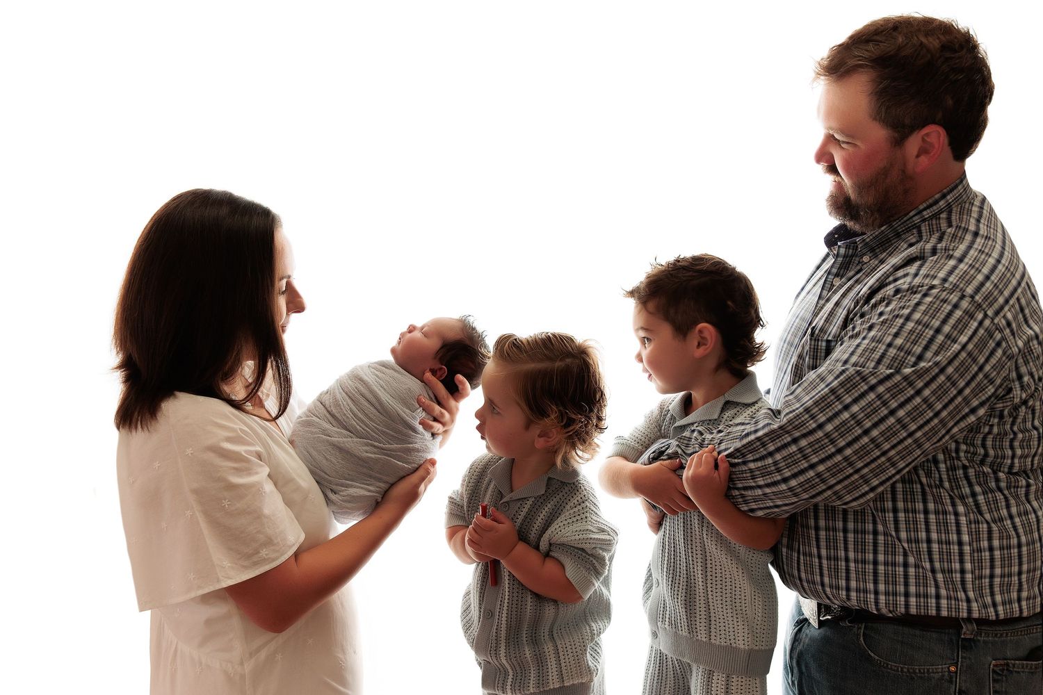 Family members standing in a row brushing their teeth together against a white background.