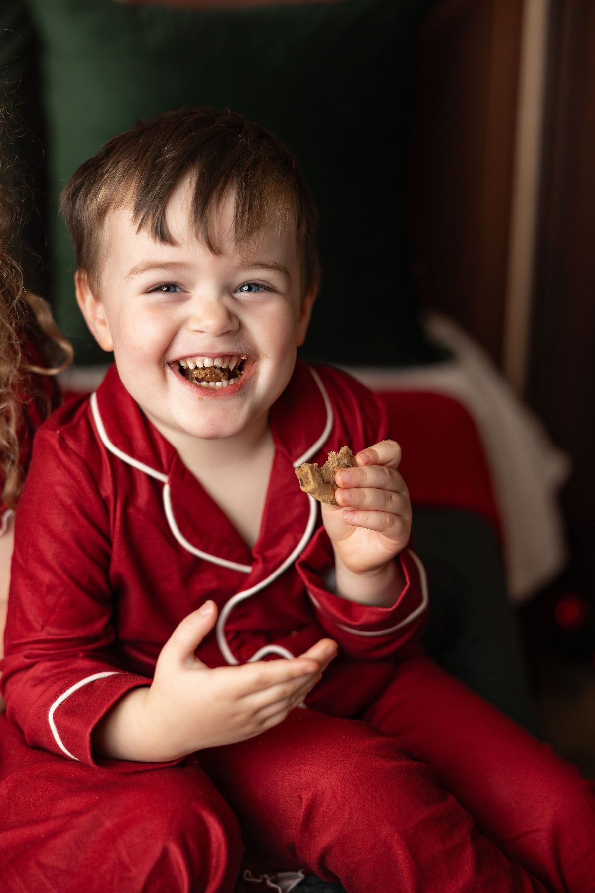 Laughing little boy in red Christmas jammies holding a cookie, Monterey Christmas mini session