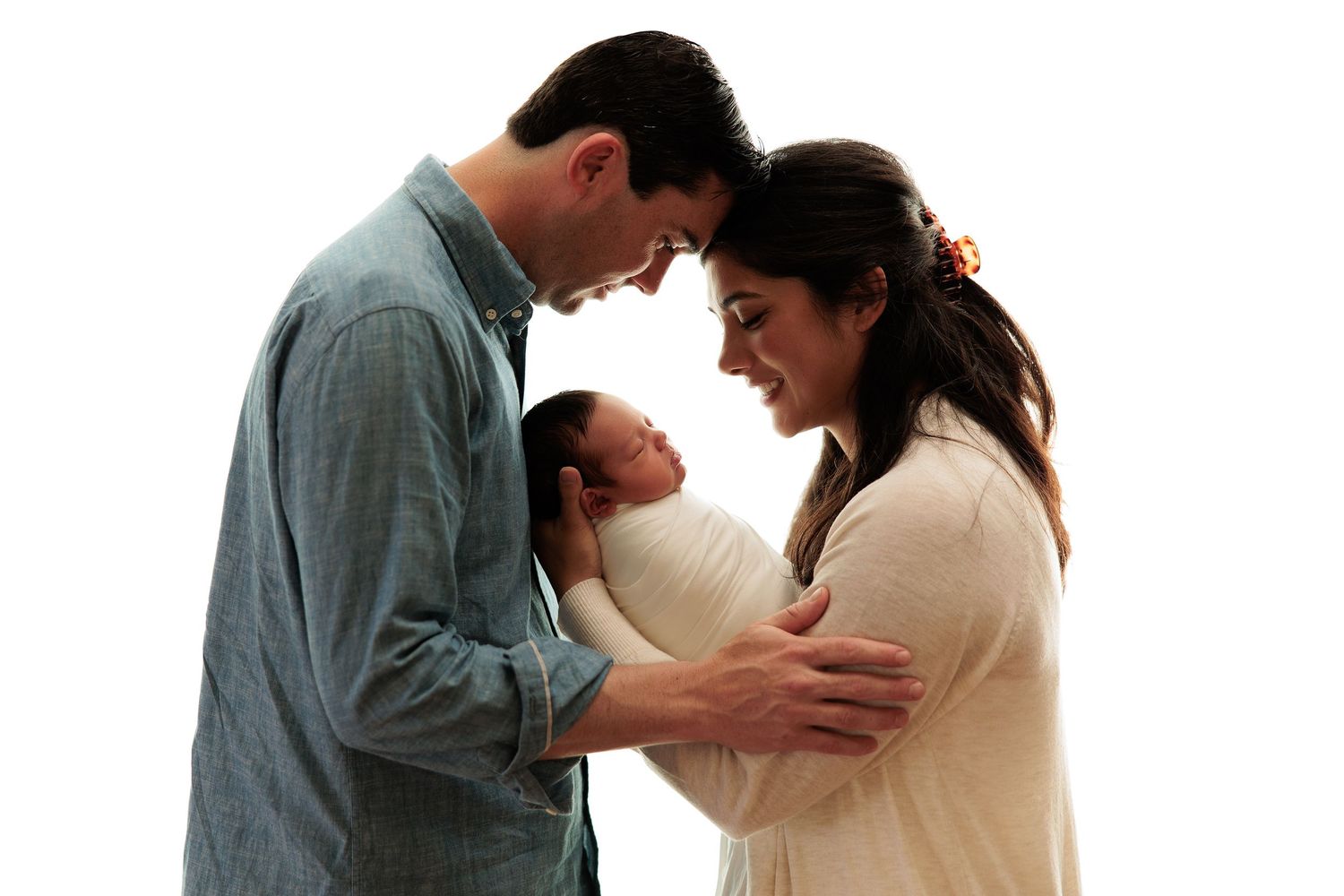 Family of three share an intimate moment together against white background.