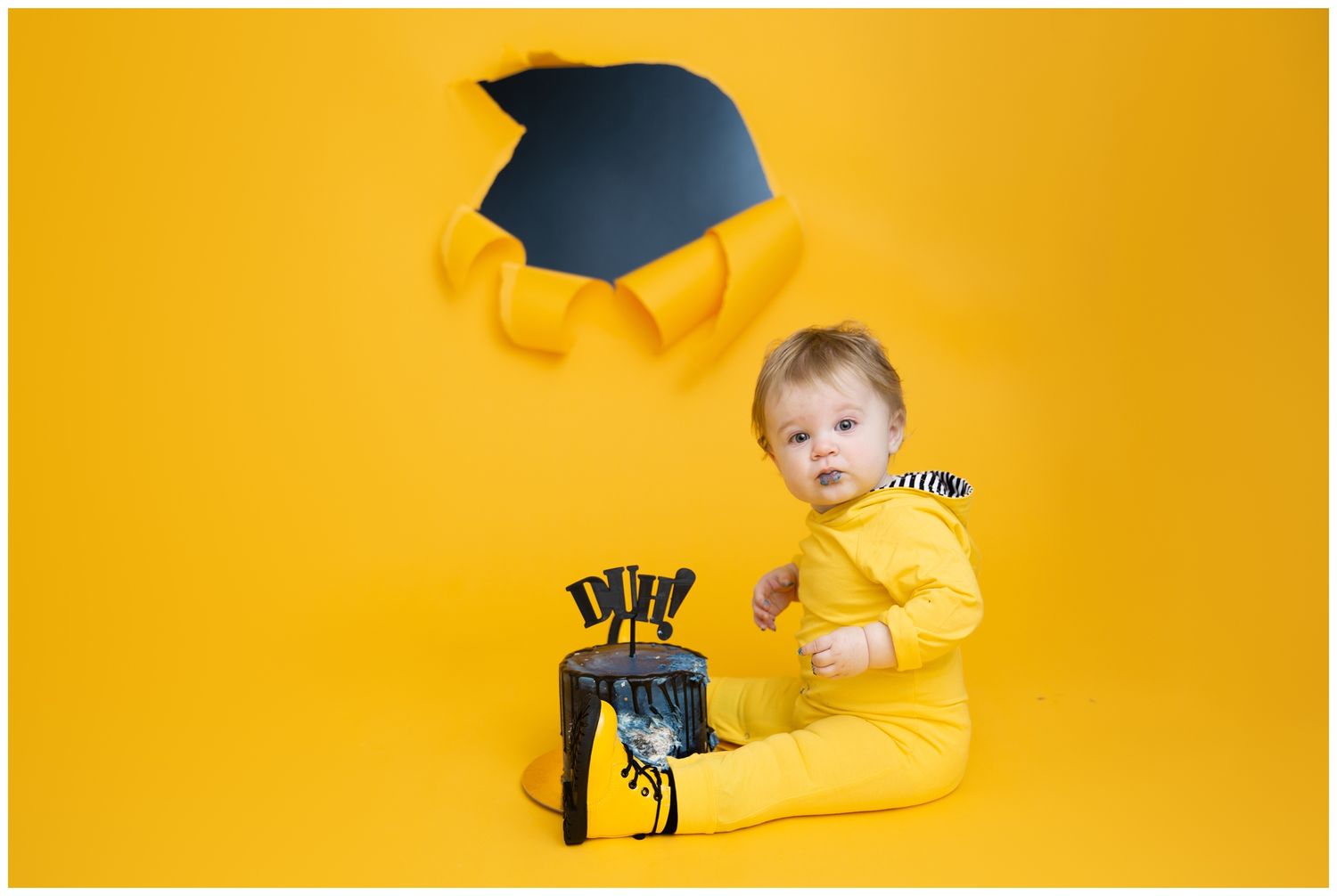 Small child wearing yellow outfit crawls and plays against bright yellow background in creative photo series.