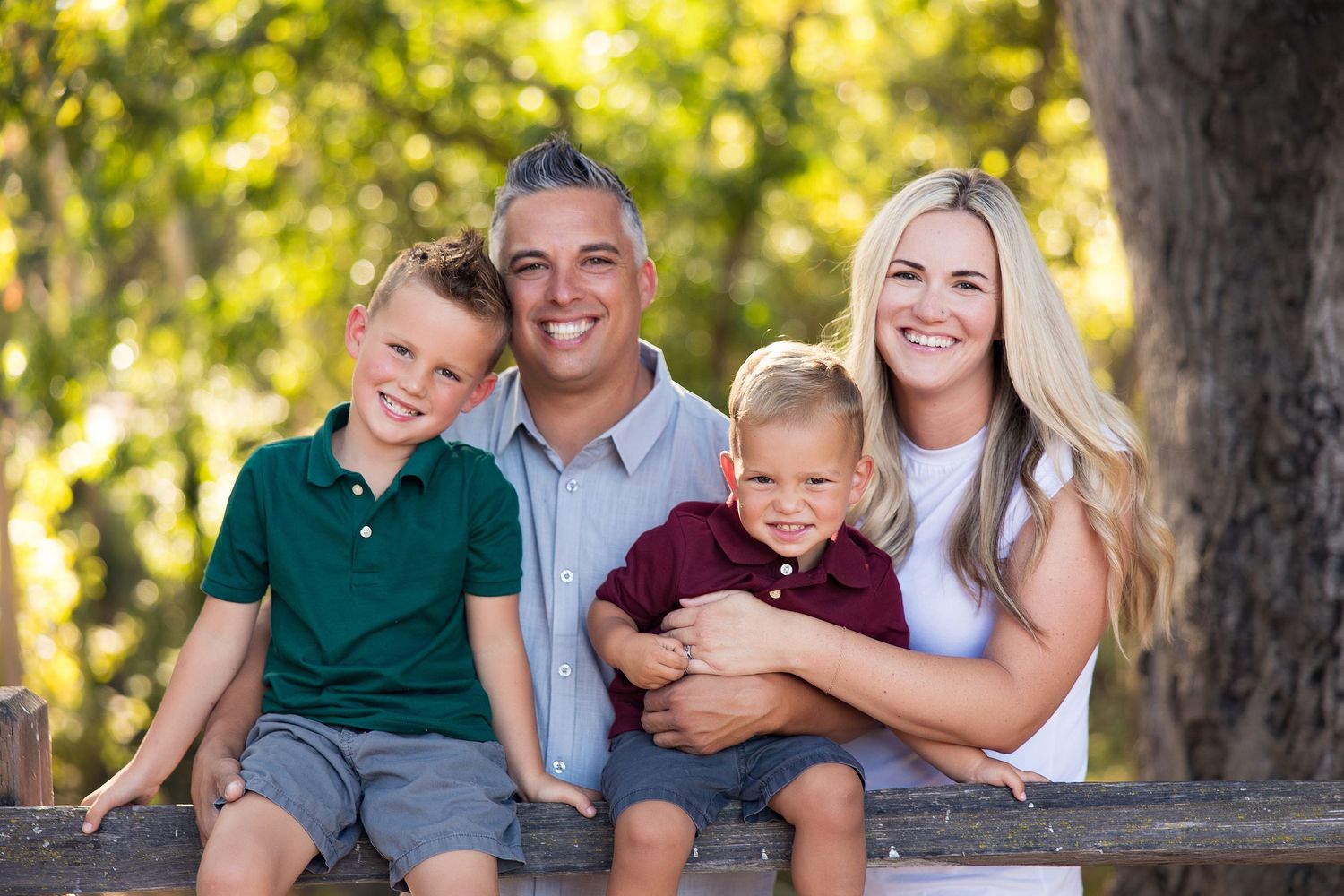 Happy family of four posing together outdoors in casual clothing.