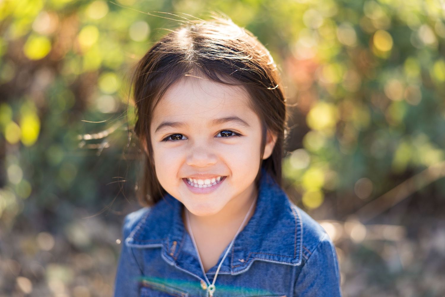 Portrait against blurred autumn foliage wearing denim jacket.