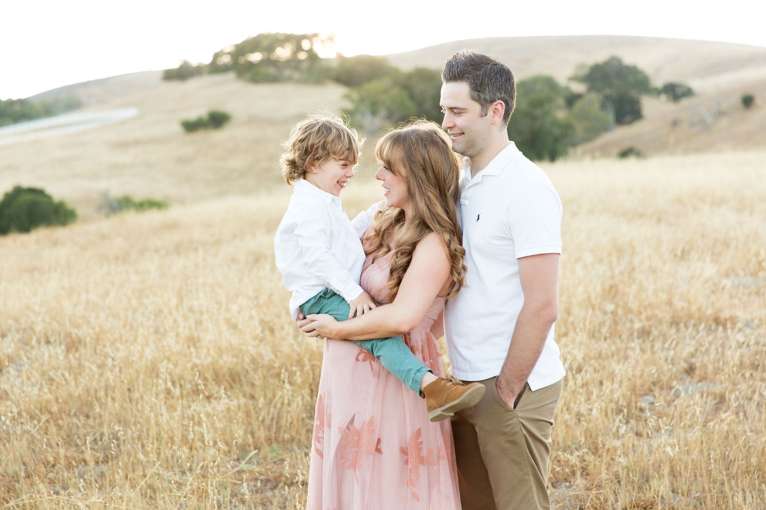Family sharing tender moment together in golden summer field.