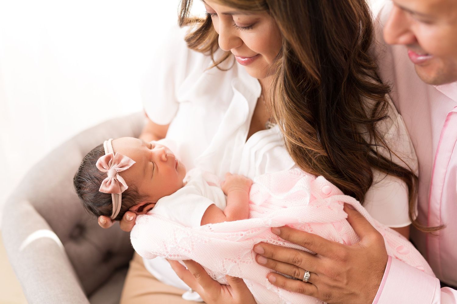 Newborn baby wrapped in pink swaddle blanket being cradled.