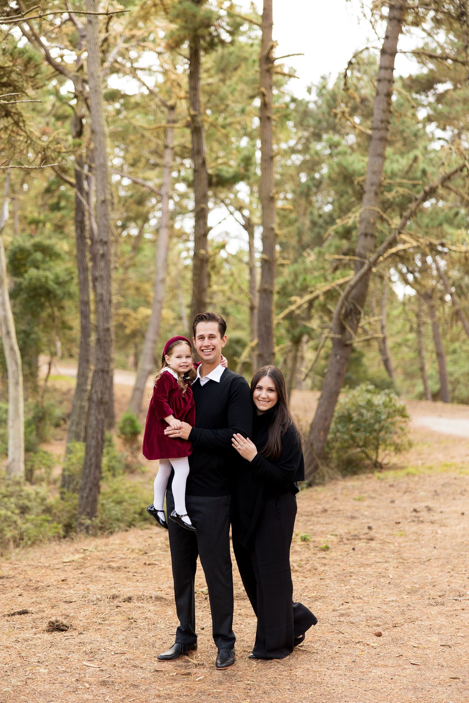Family portrait session in a pine forest in Pacific Grove with group members in formal black attire.