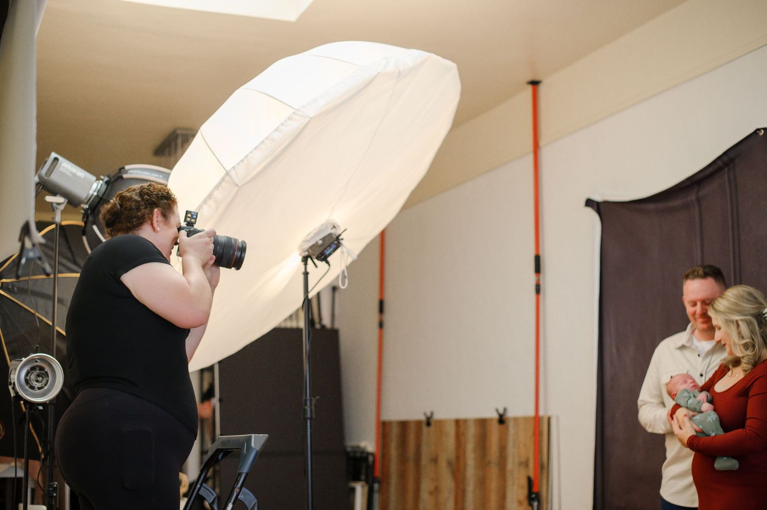 Professional photographer using studio lighting equipment and a large diffuser during an indoor portrait photography session.