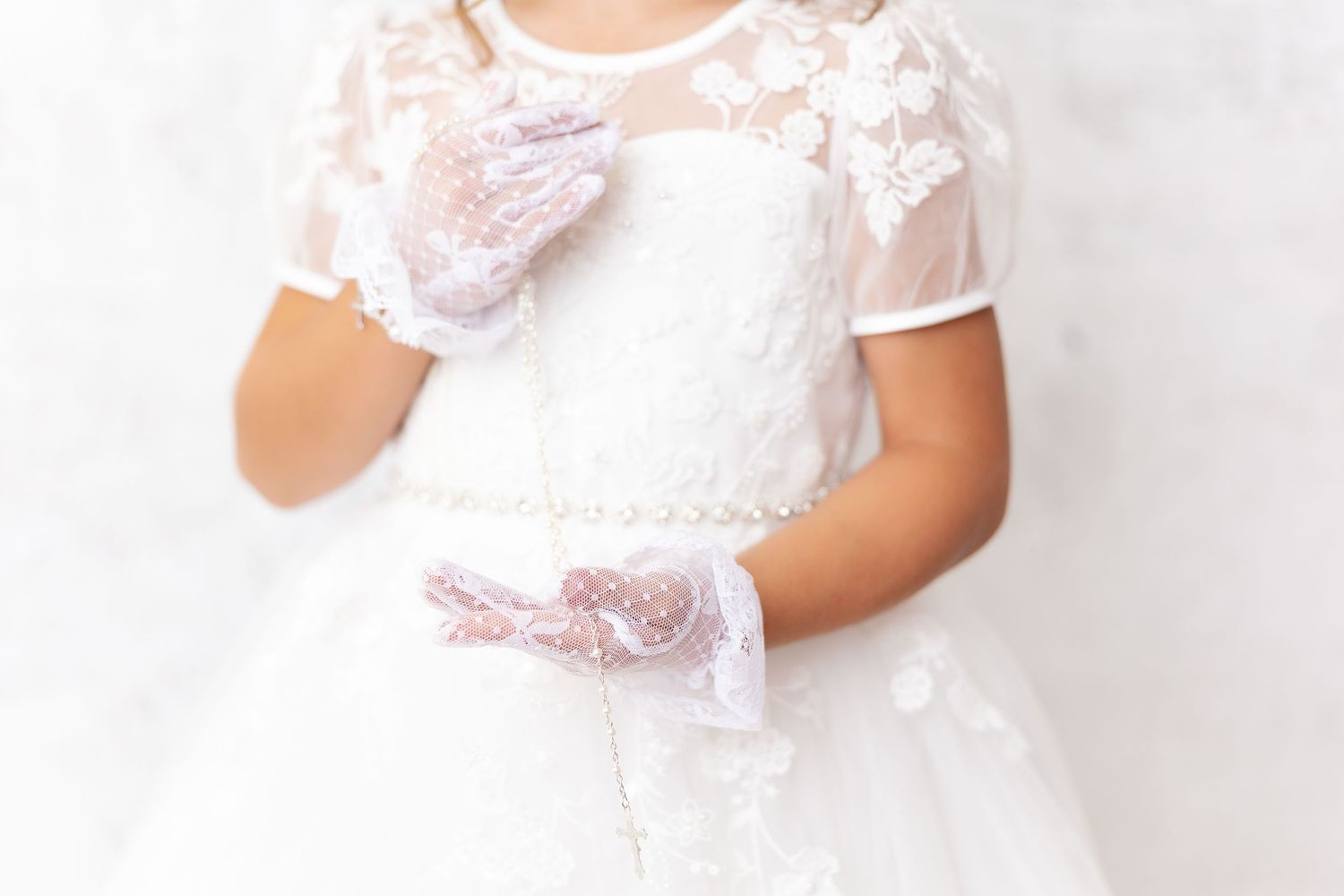 White lace dress with matching gloves captured against a light gray background.