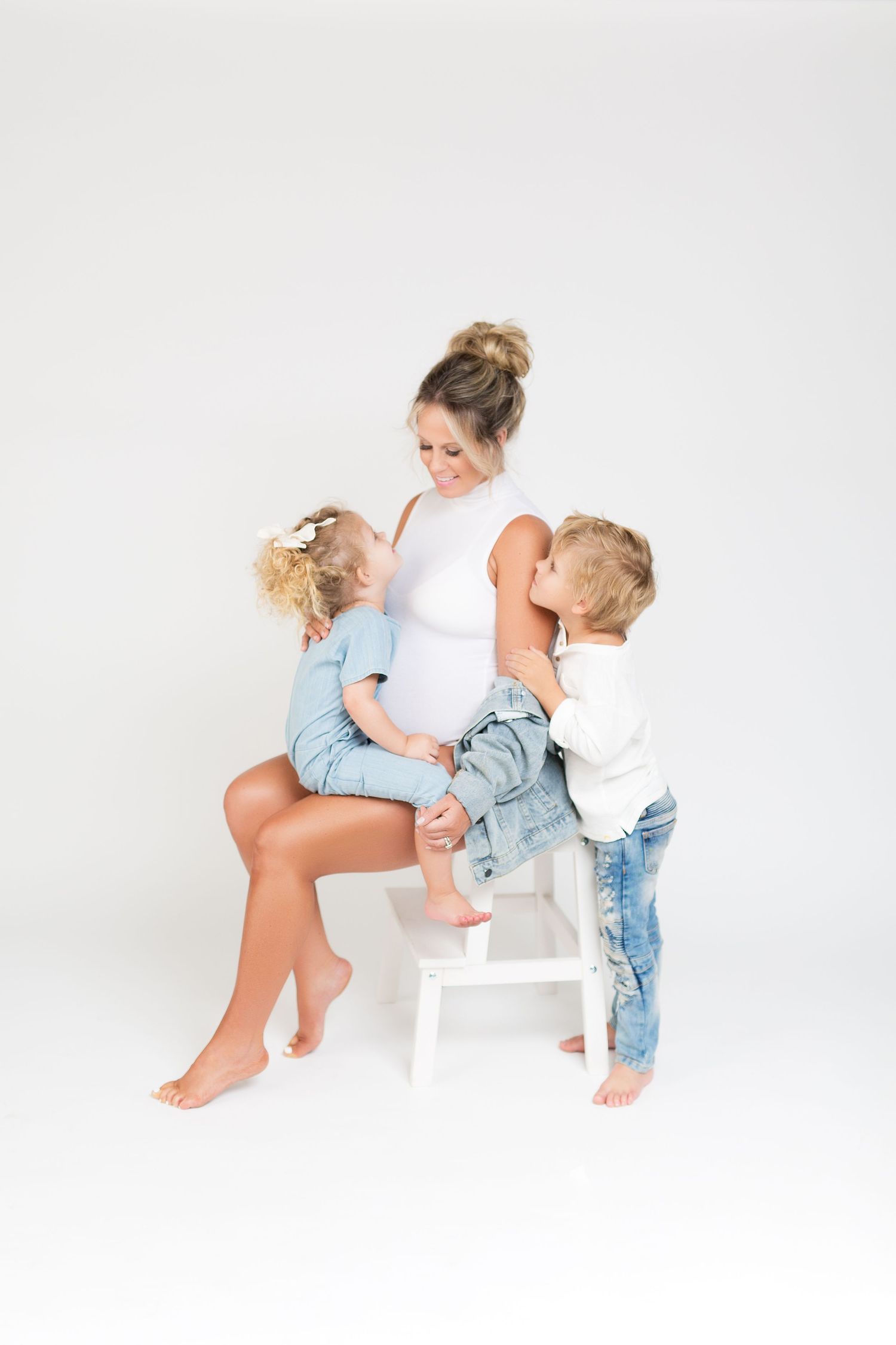 Sweet candid moments captured during white studio maternity photoshoot.