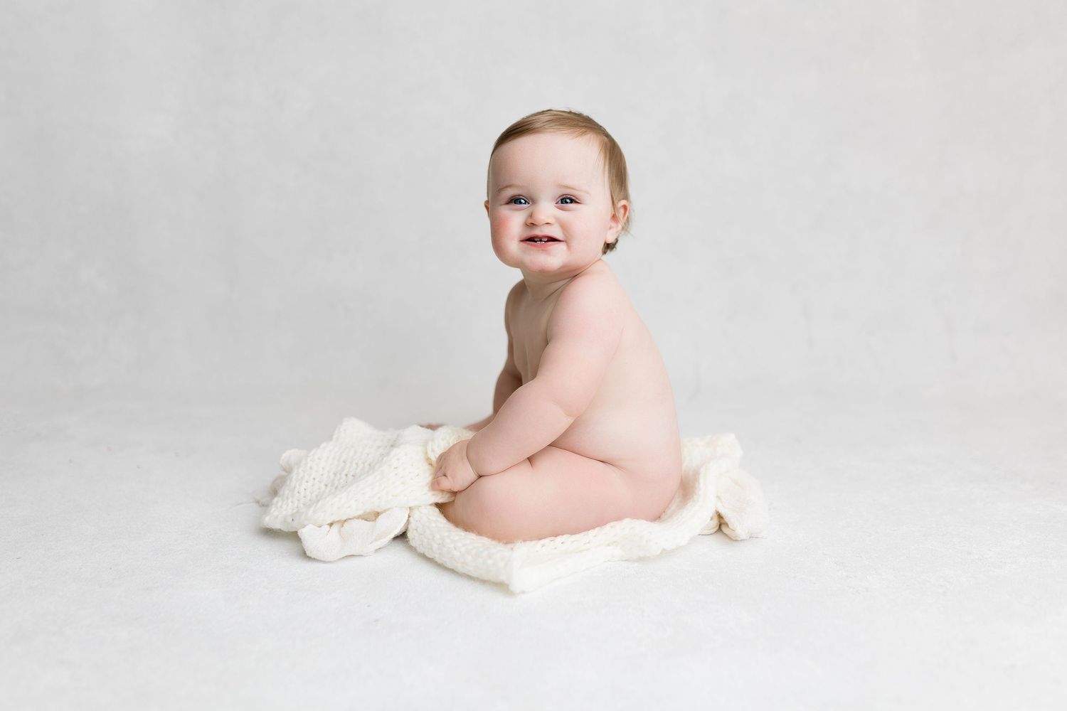 Simple studio portrait with white backdrop and soft fabric wrap.