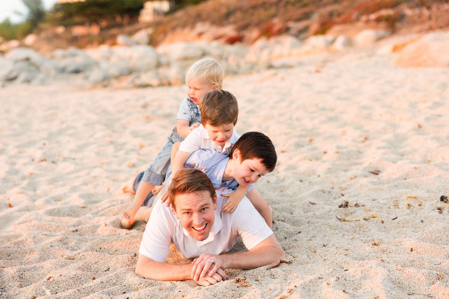 Family plays together on sandy beach during sunset.