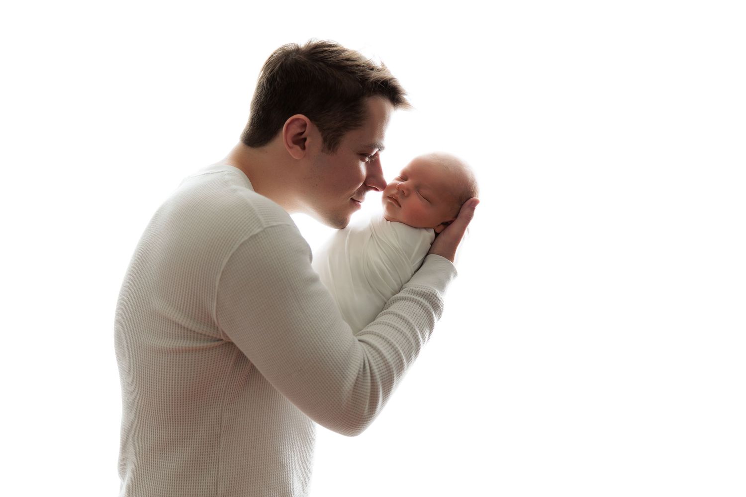 A tender moment between parent and newborn baby against a white background.