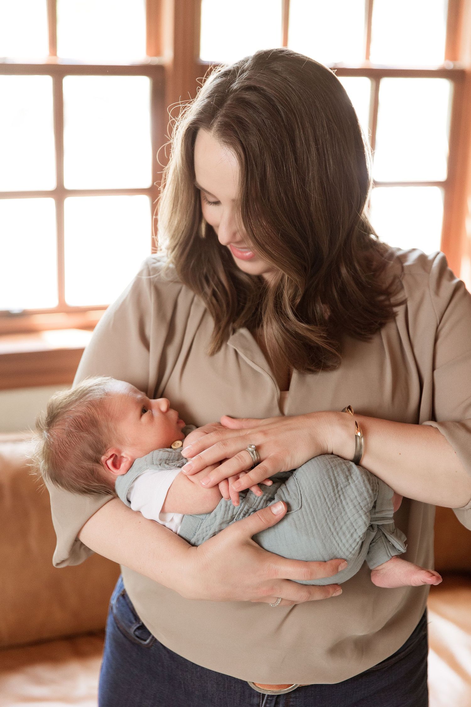 Tender moments captured between parent and newborn baby in warm sunlit room.