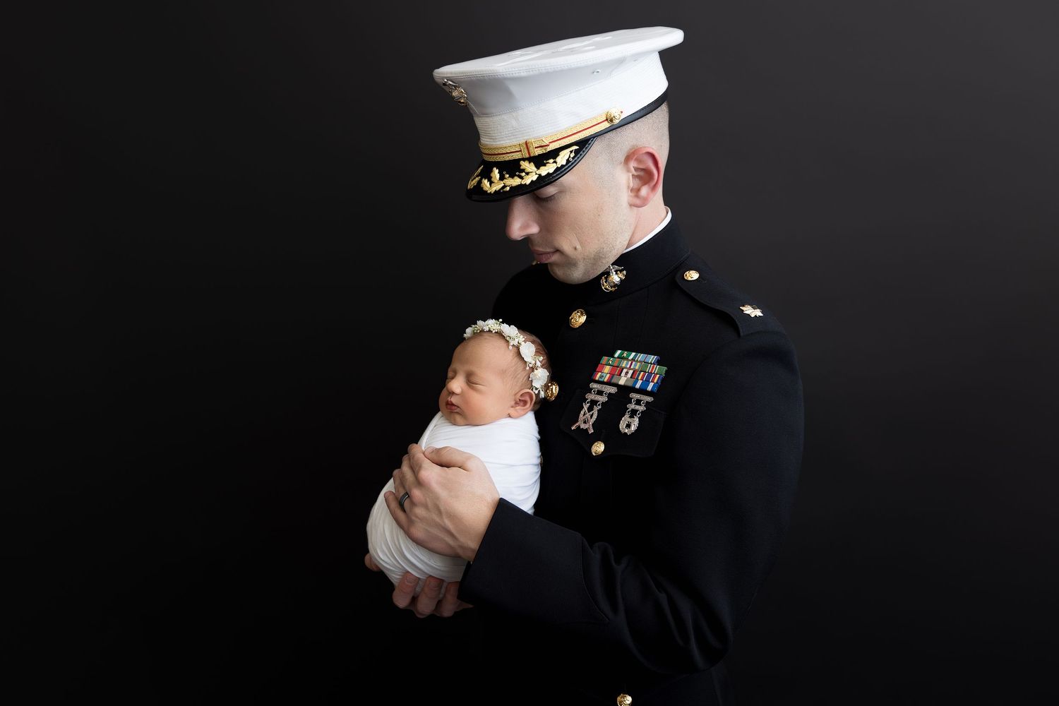 Military service member in dress uniform holds newborn baby in heartwarming photo series.