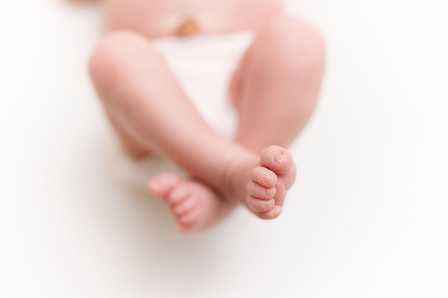 Close-up view of tiny baby feet and toes against white background.