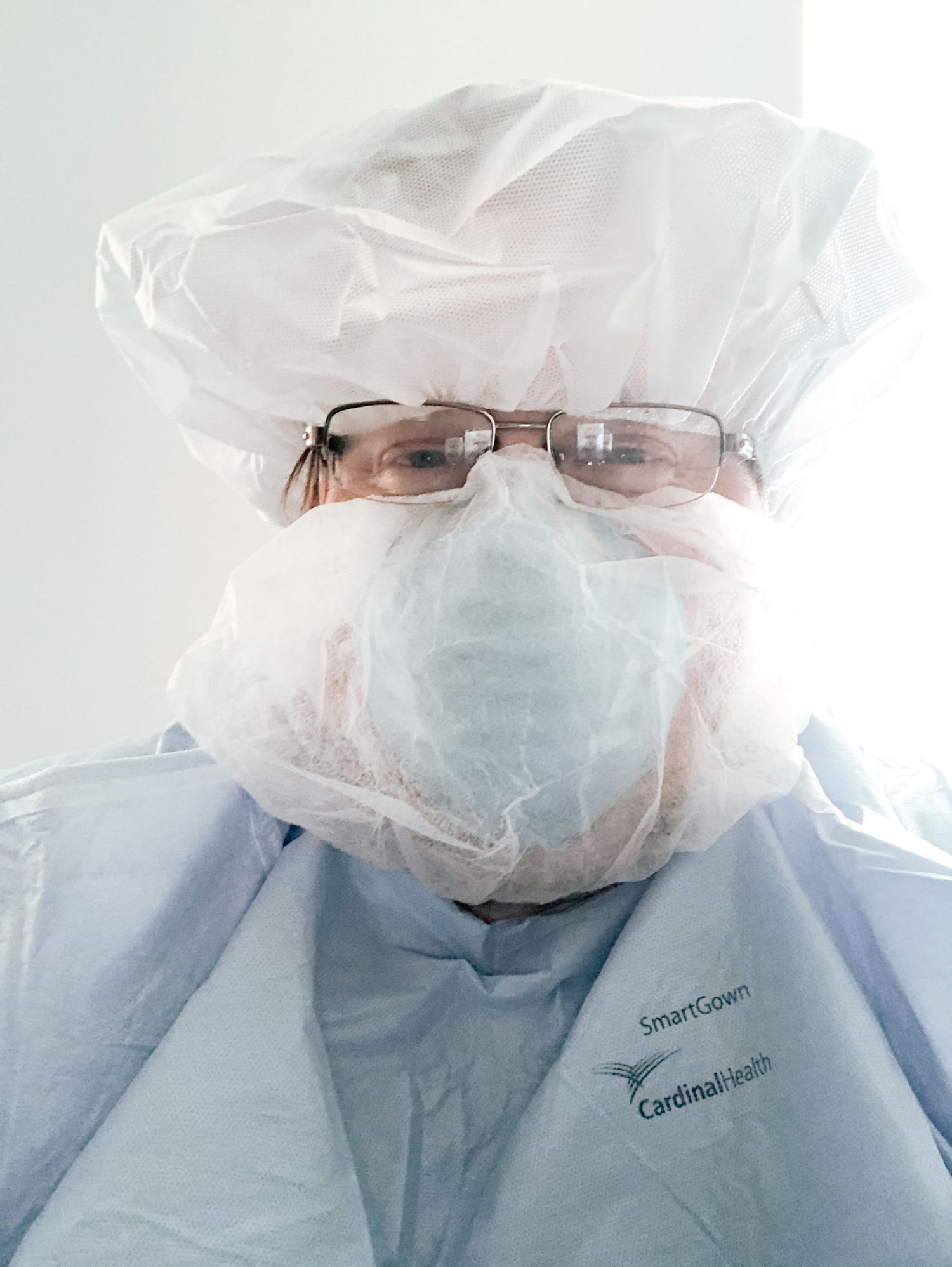 Medical professionals wearing protective gear and face masks look at the camera in a healthcare setting.