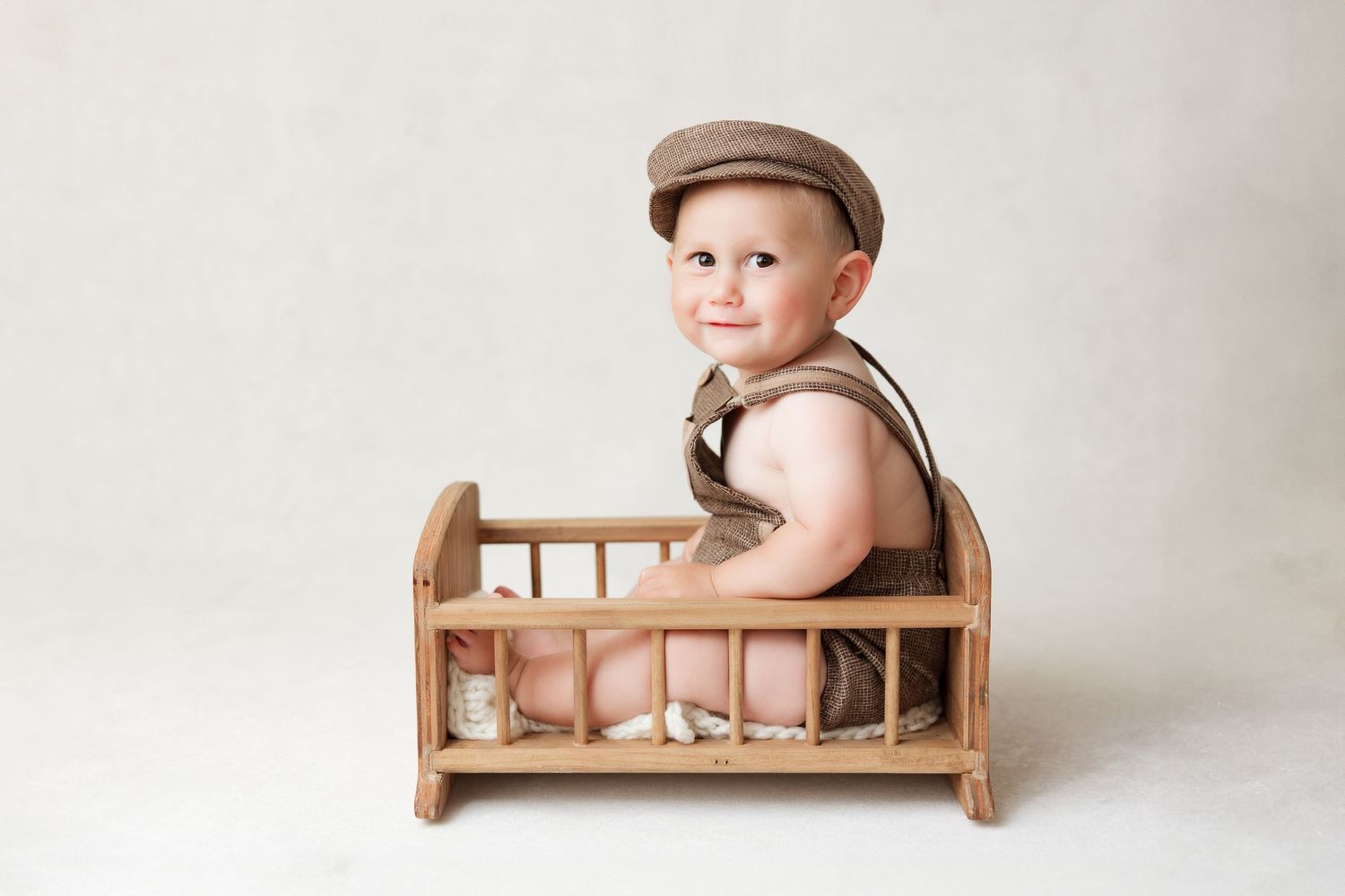 Rustic wooden photography props including small beds and benches against neutral background.