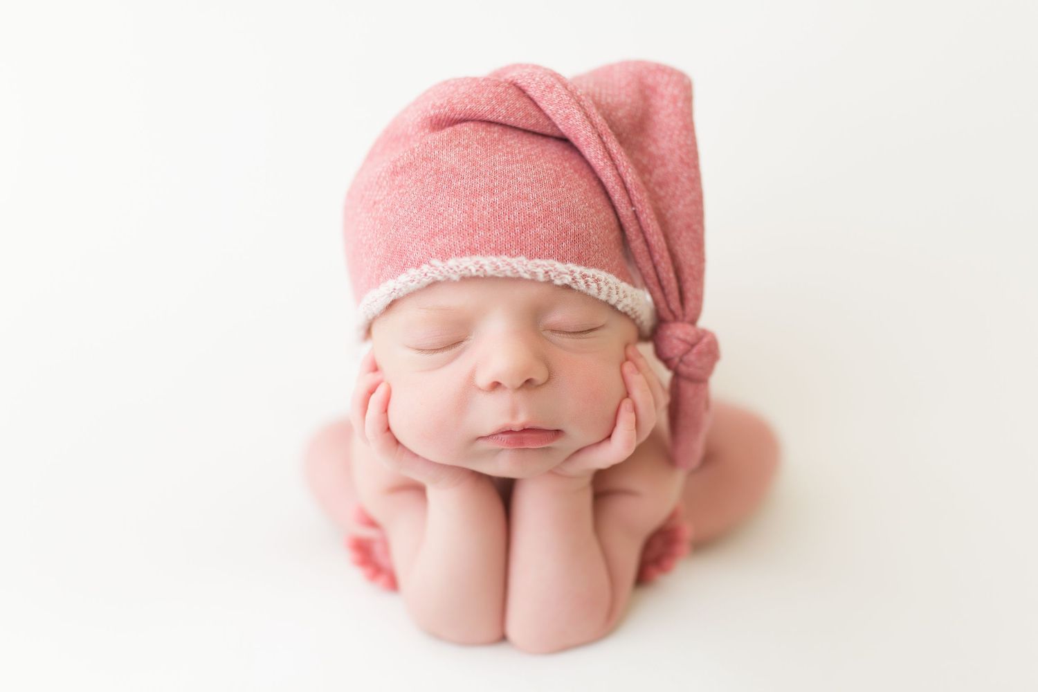 Sweet newborn baby details wearing pink bonnet during professional photo session.