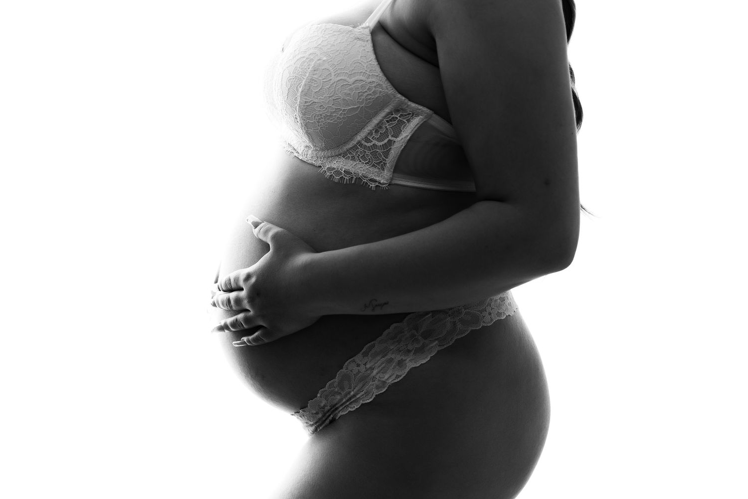 Black and white silhouette of pregnant belly in lace lingerie.
