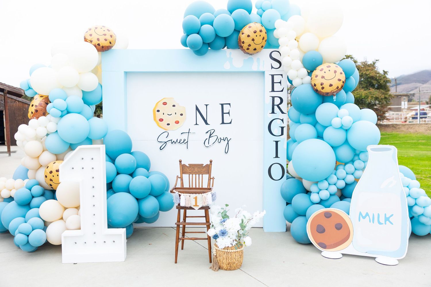 Blue and white balloon arch with cookie decorations and milk theme party decor creates a sweet celebration setup.
