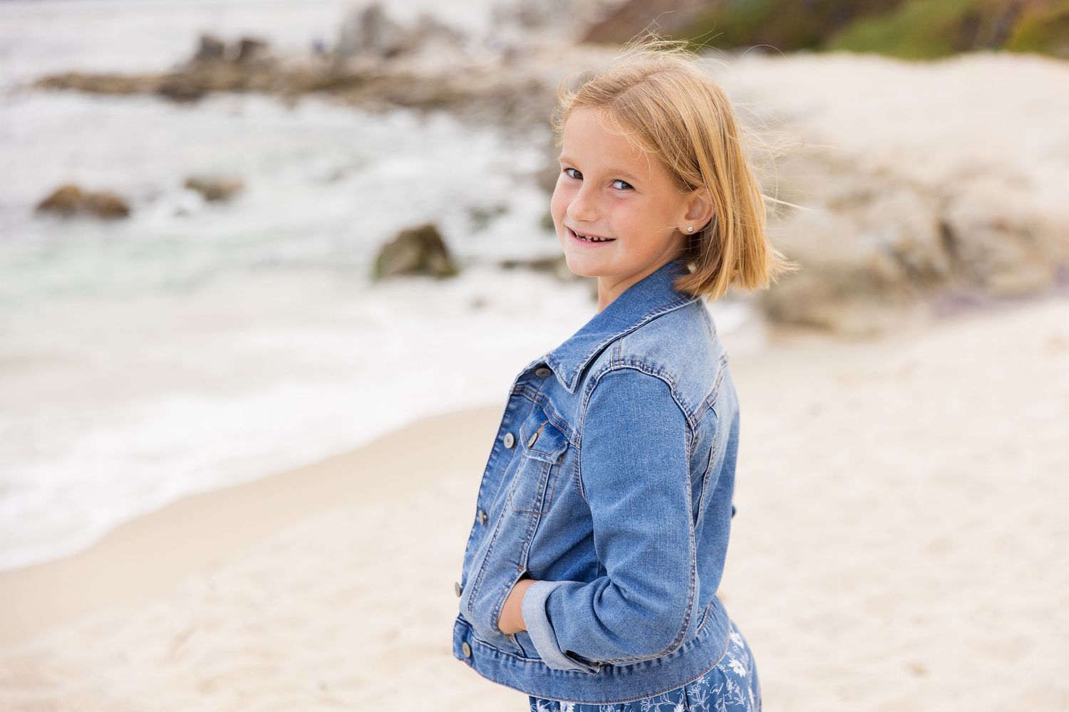 Children run and play along a beautiful beach with rocky cliffs.