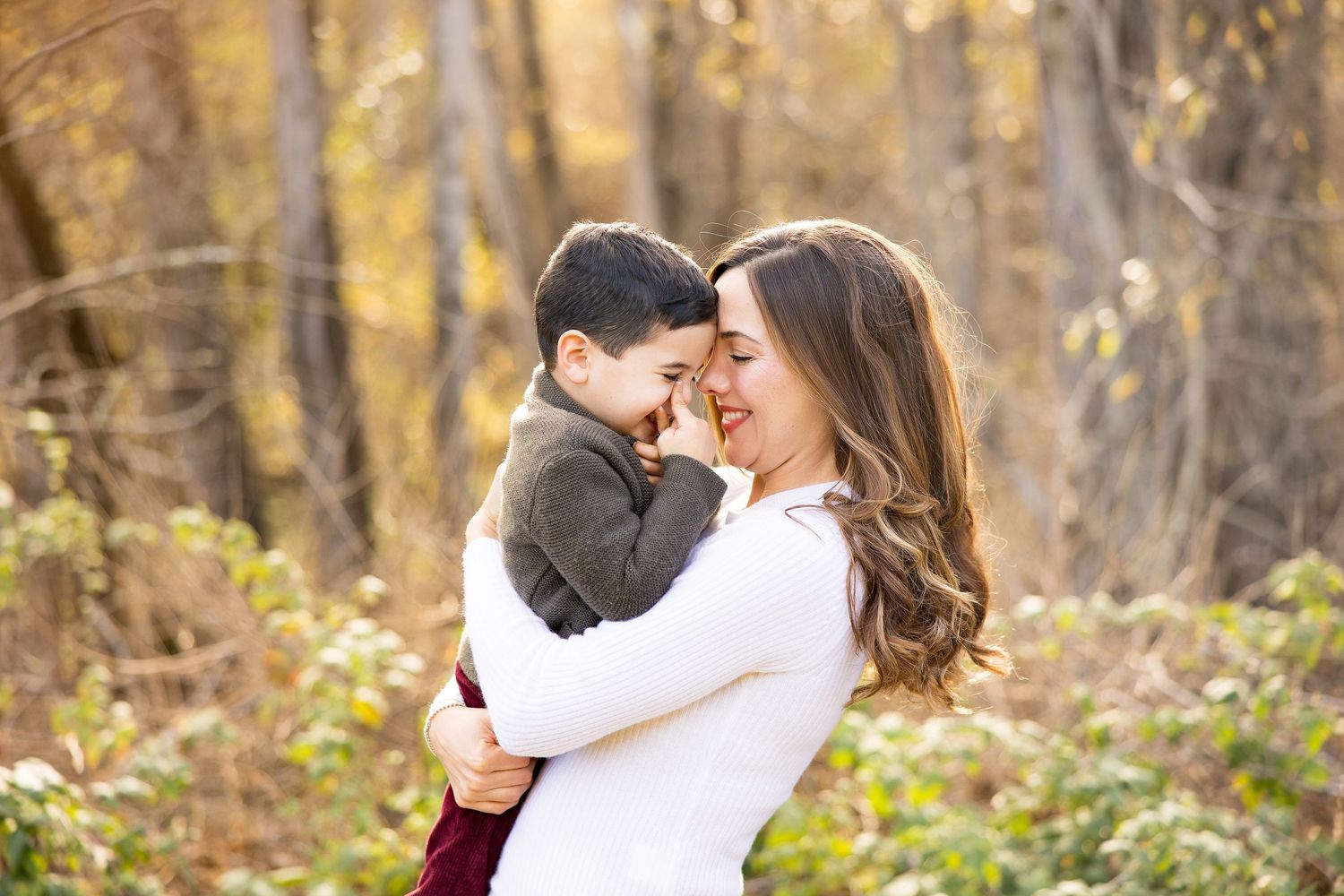 A tender moment between two people sharing an embrace in an autumn forest with golden leaves in the background.
