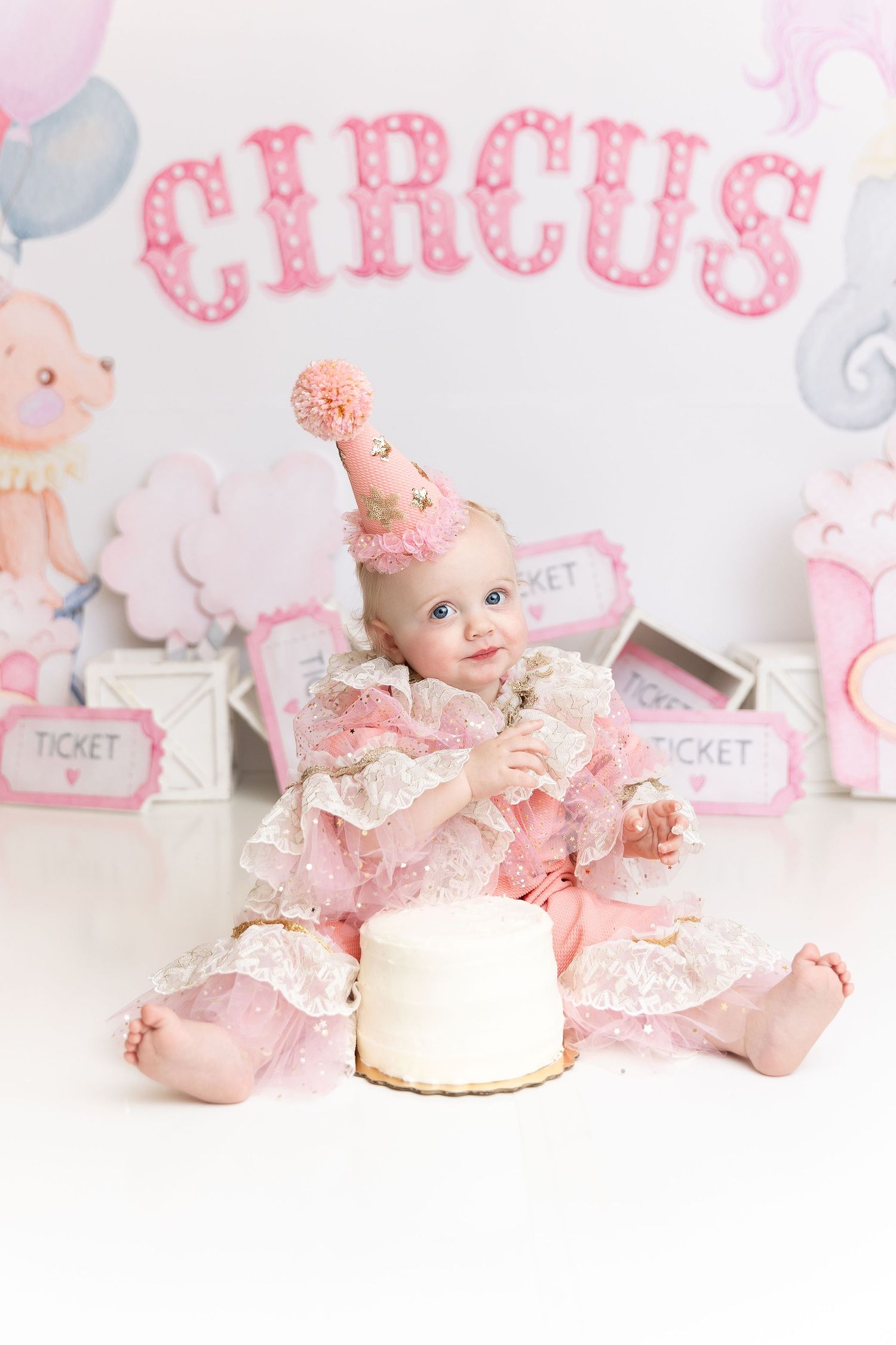 Pink circus-themed cake smash setup with white cake, balloons, and party decorations.