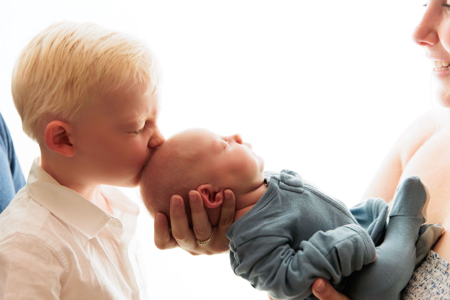 Sweet moment between siblings with newborn baby.