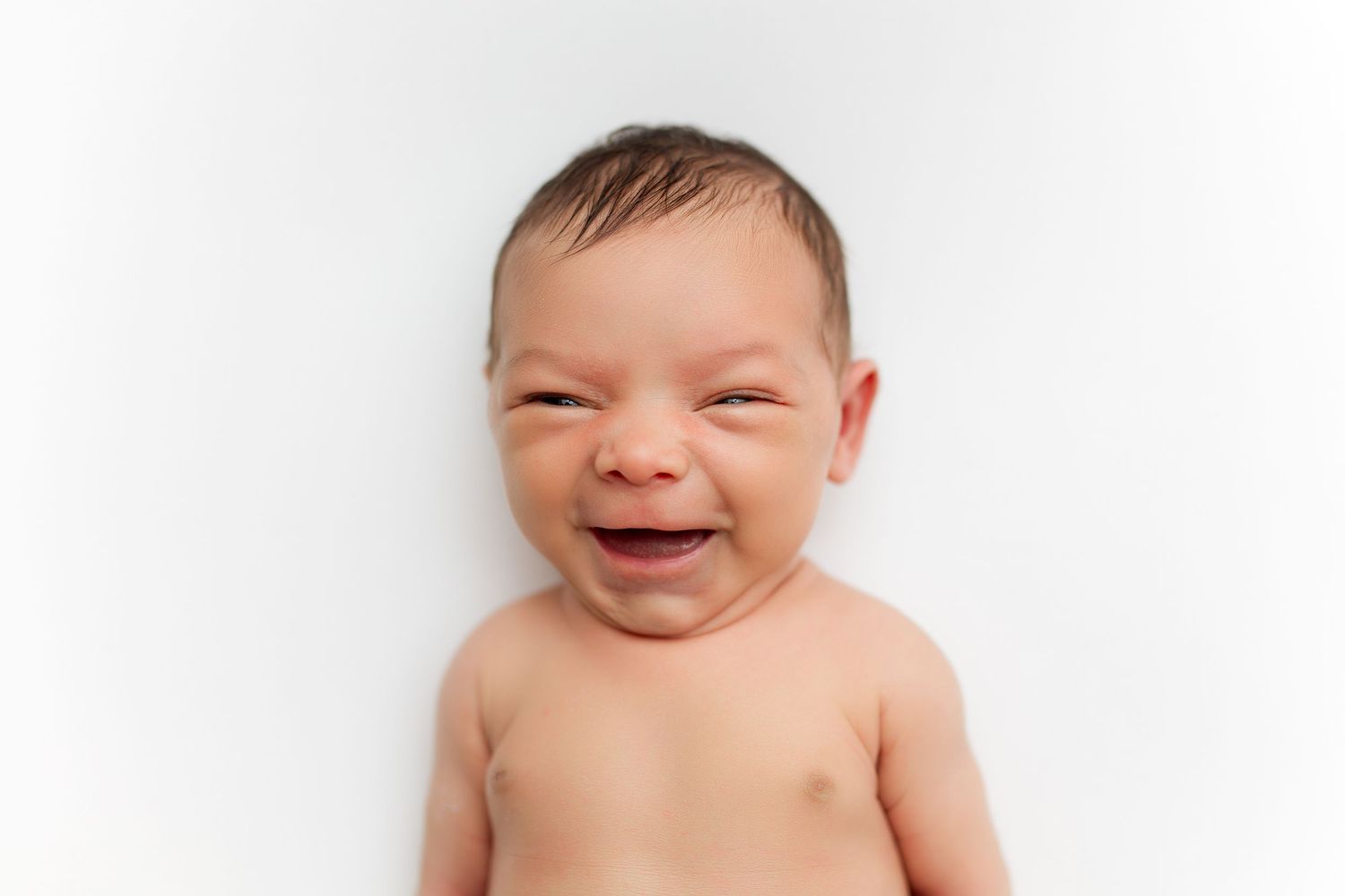 Close-up portrait of laughing baby against white background.