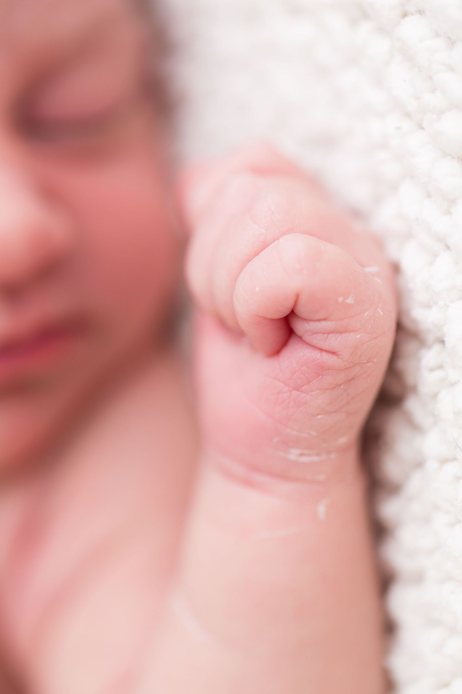 A soft focus macro portrait showing baby lips and skin in gentle pink tones and white fabric.