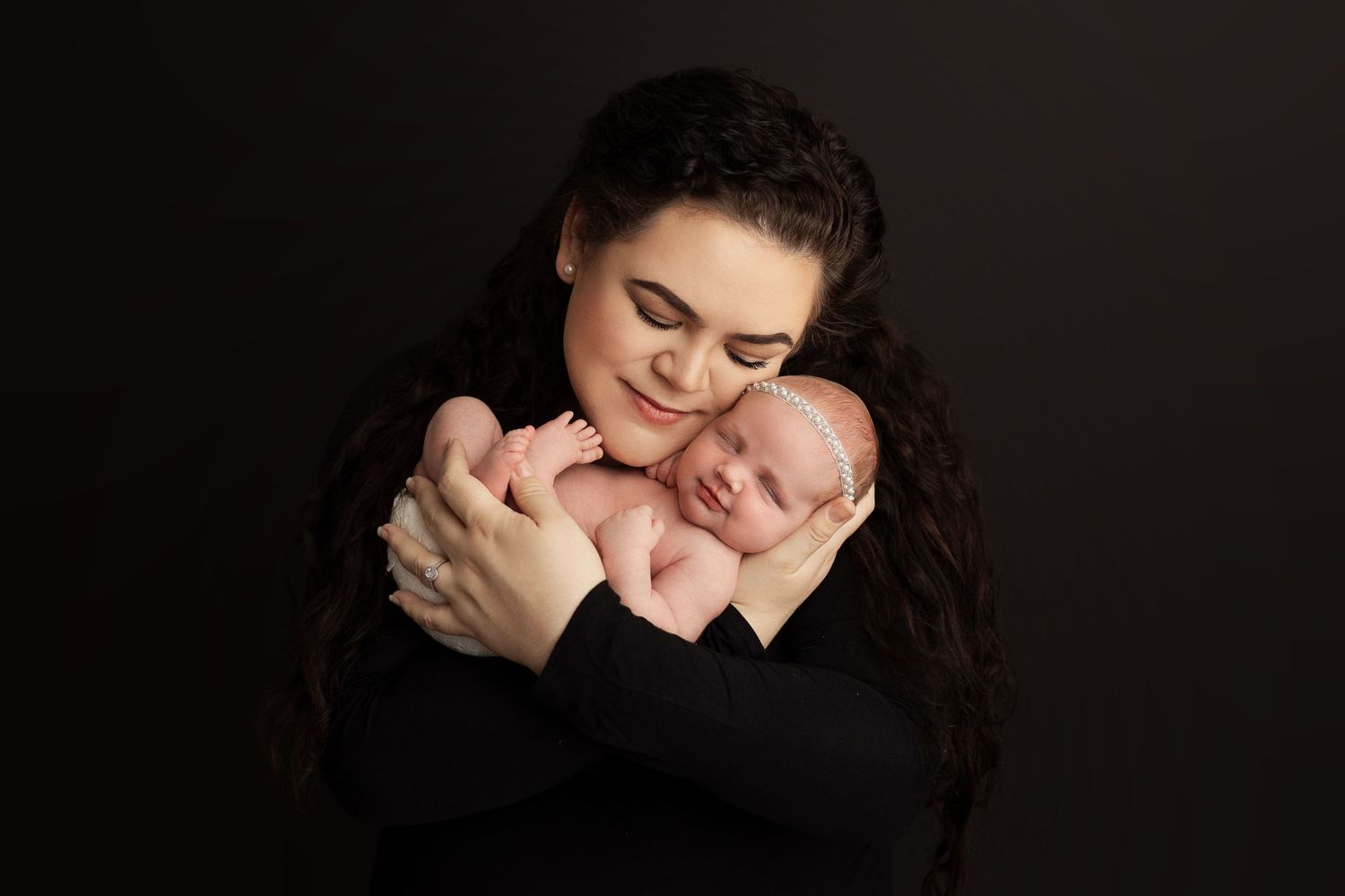 Intimate family portrait session with dramatic black backdrop and tender moments.