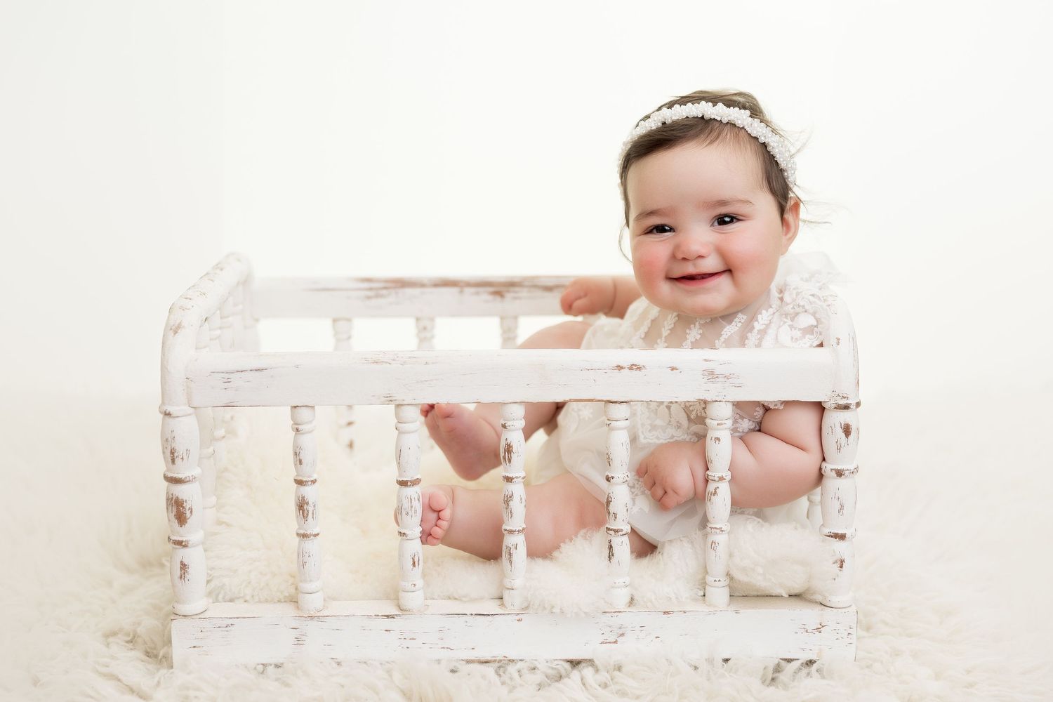 Baby relaxing in vintage white crate on fluffy rug.