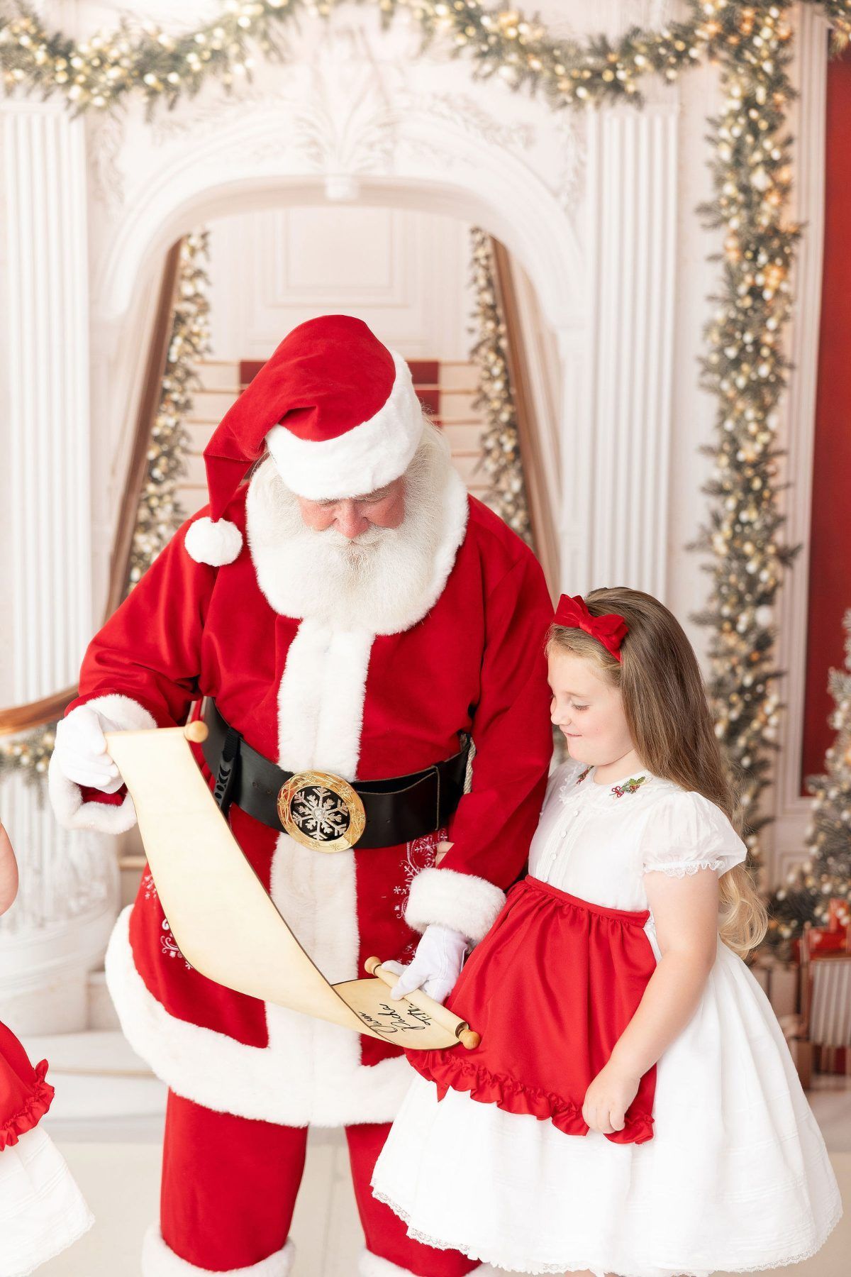 Santa showing a little girl the Nice List during a Christmas mini session in Monterey